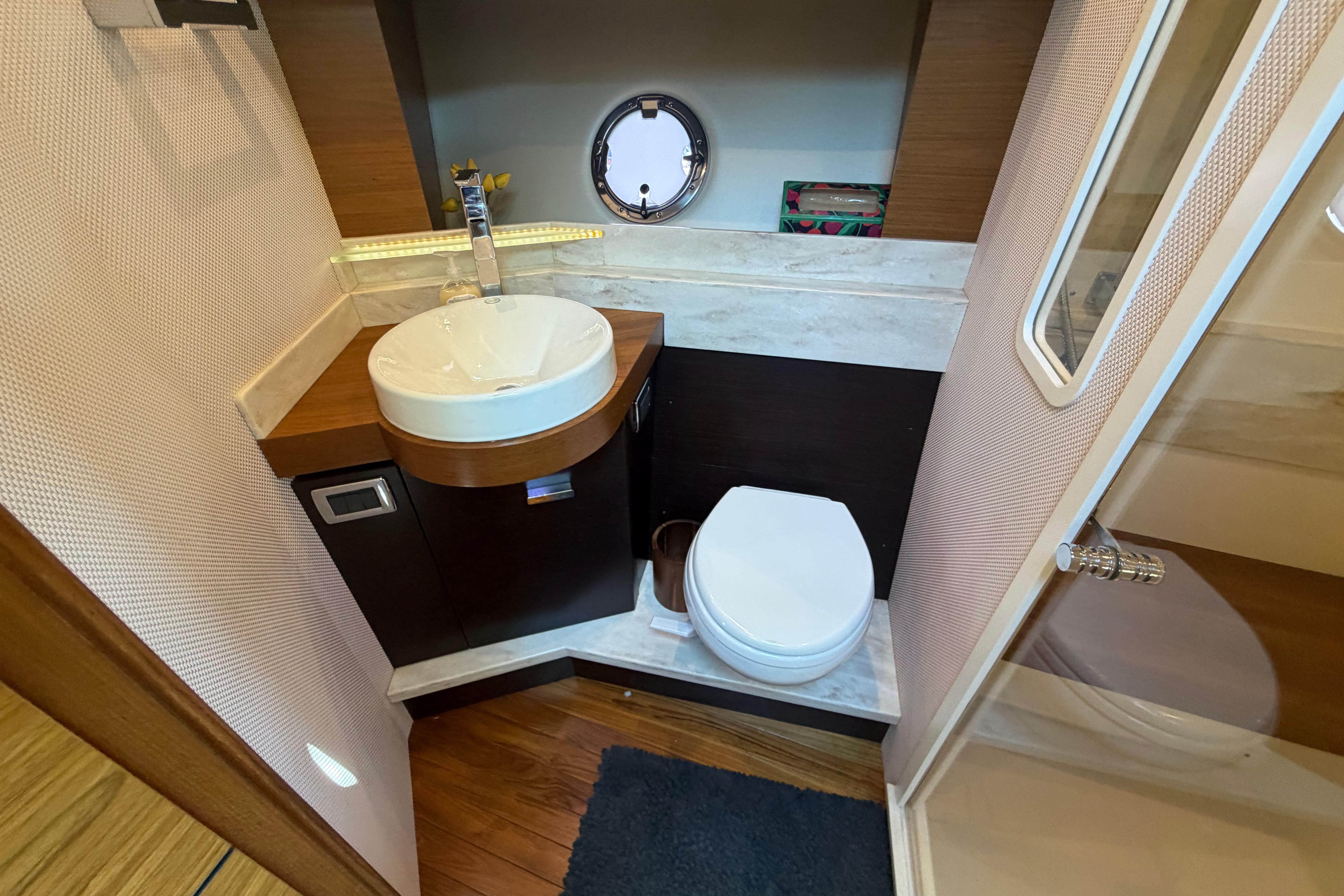 Bathroom interior of 2016 Tiara Yachts C39 Coupe with sink, toilet, and porthole.