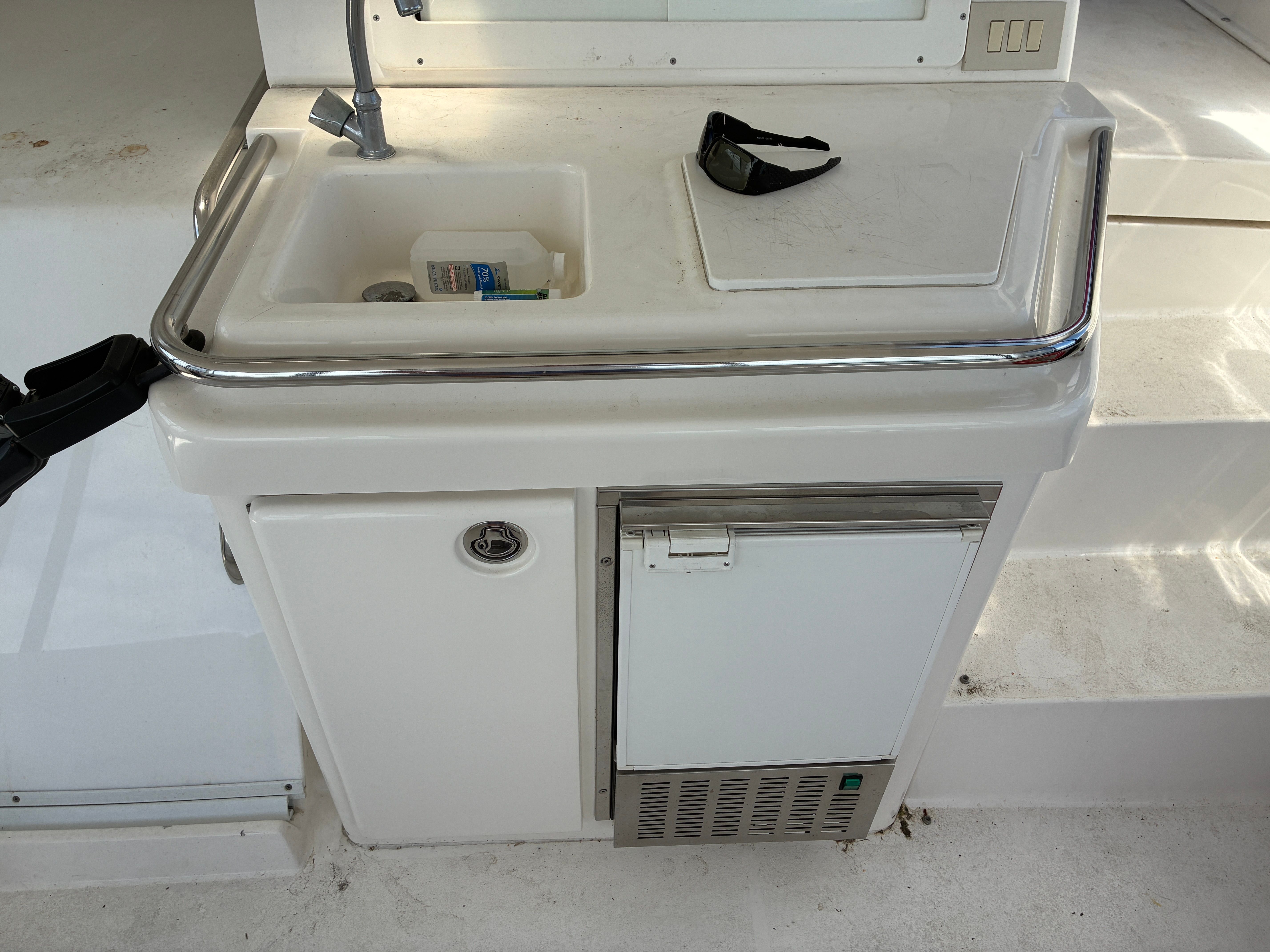 A small kitchenette with a sink and fridge on a yacht.