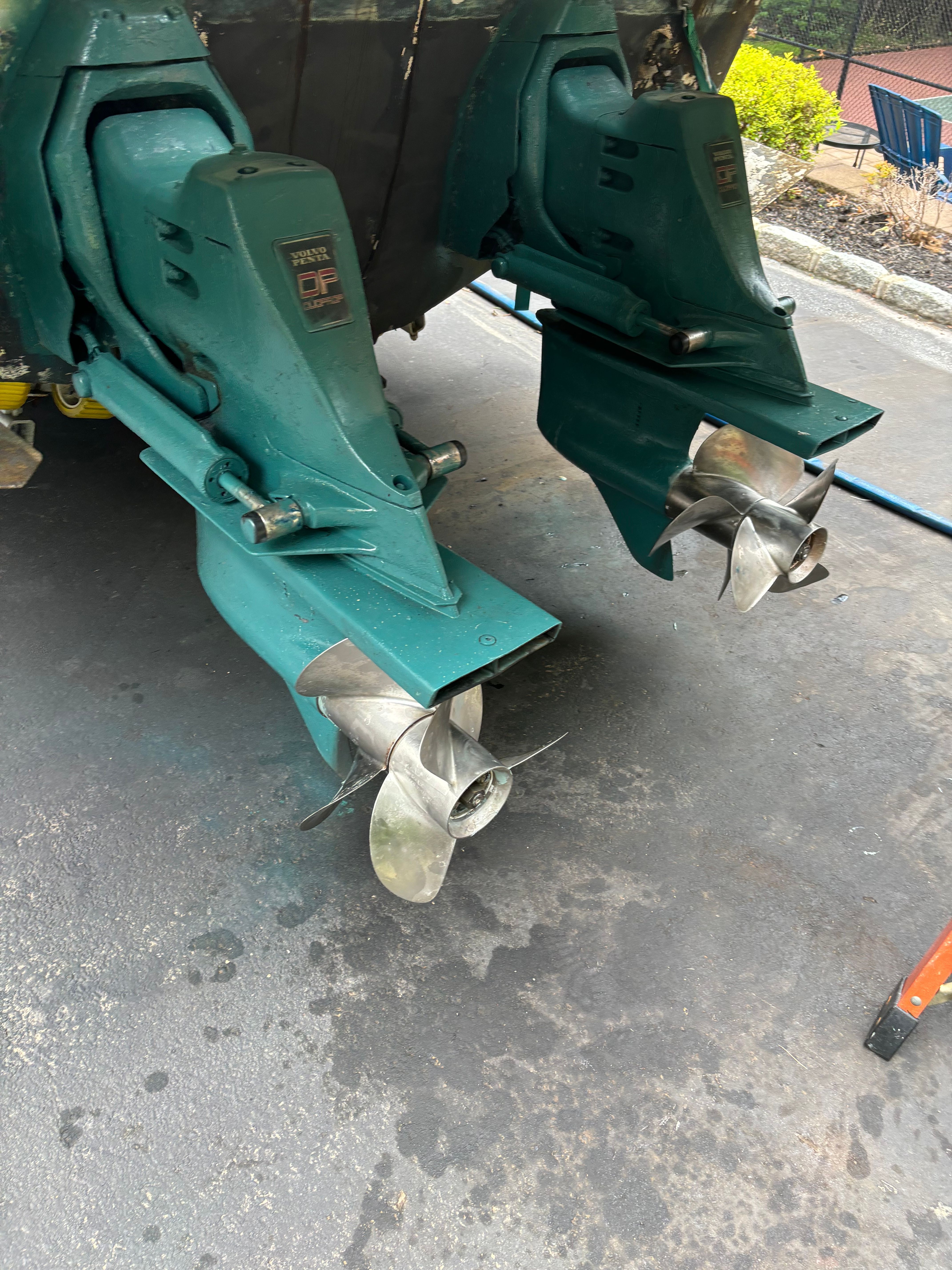 Two green boat engines with propellers on a parking lot.