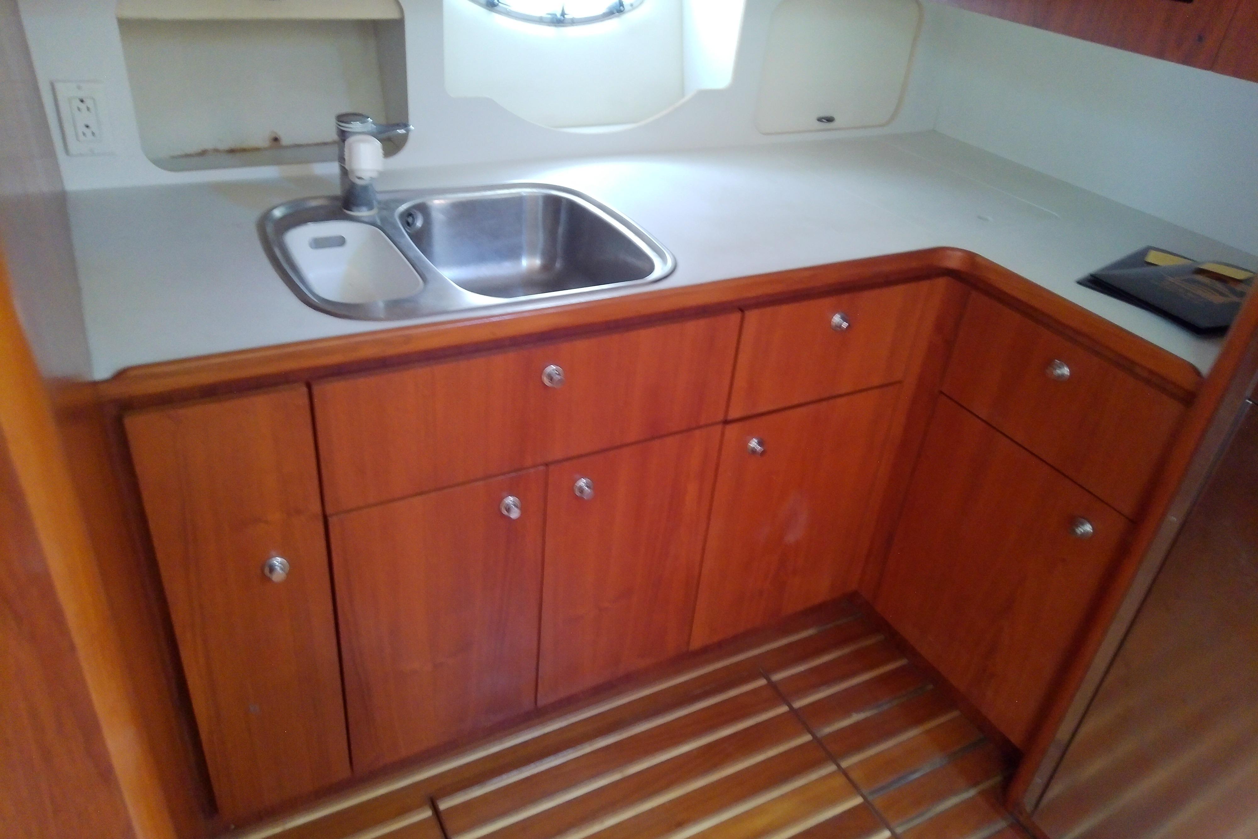 Wooden yacht kitchen with sink, cabinets, and countertop on a 2000 Tiara Yachts 4100 Open.