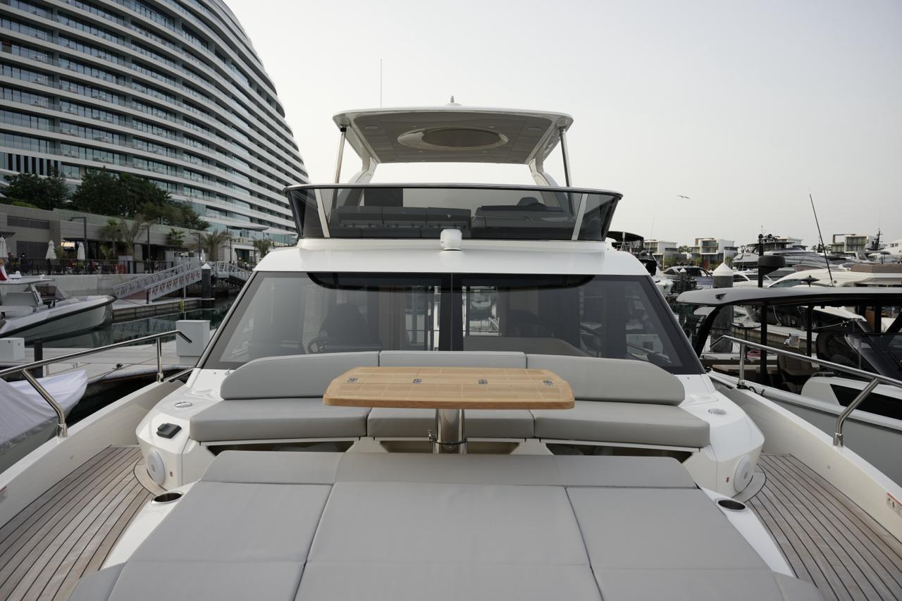 Luxury Absolute 52 FLY yacht, 2025 model, docked at marina with modern architecture.
