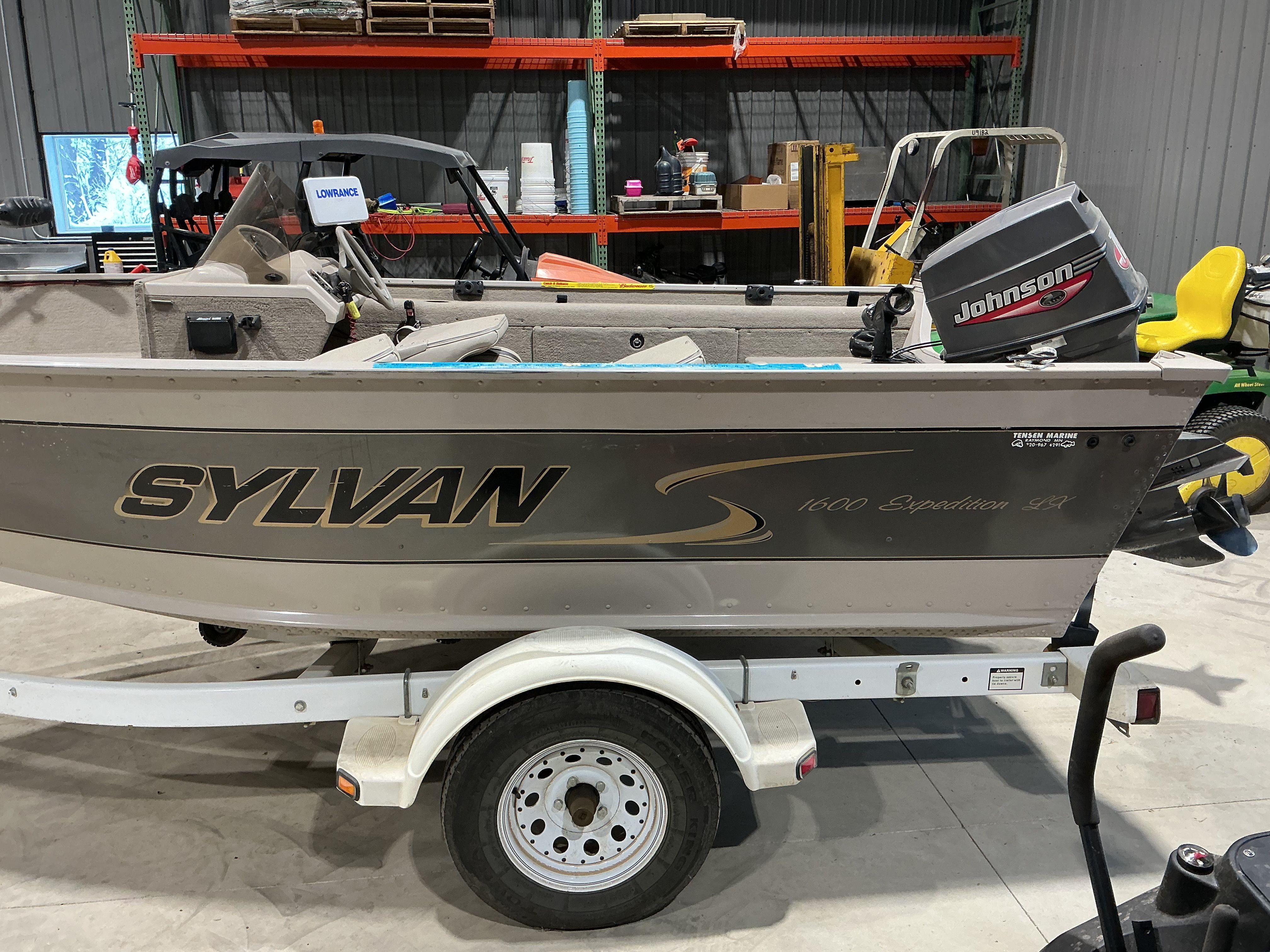 1999 Sylvan EXPEDITION boat with Johnson outboard motor in workshop.
