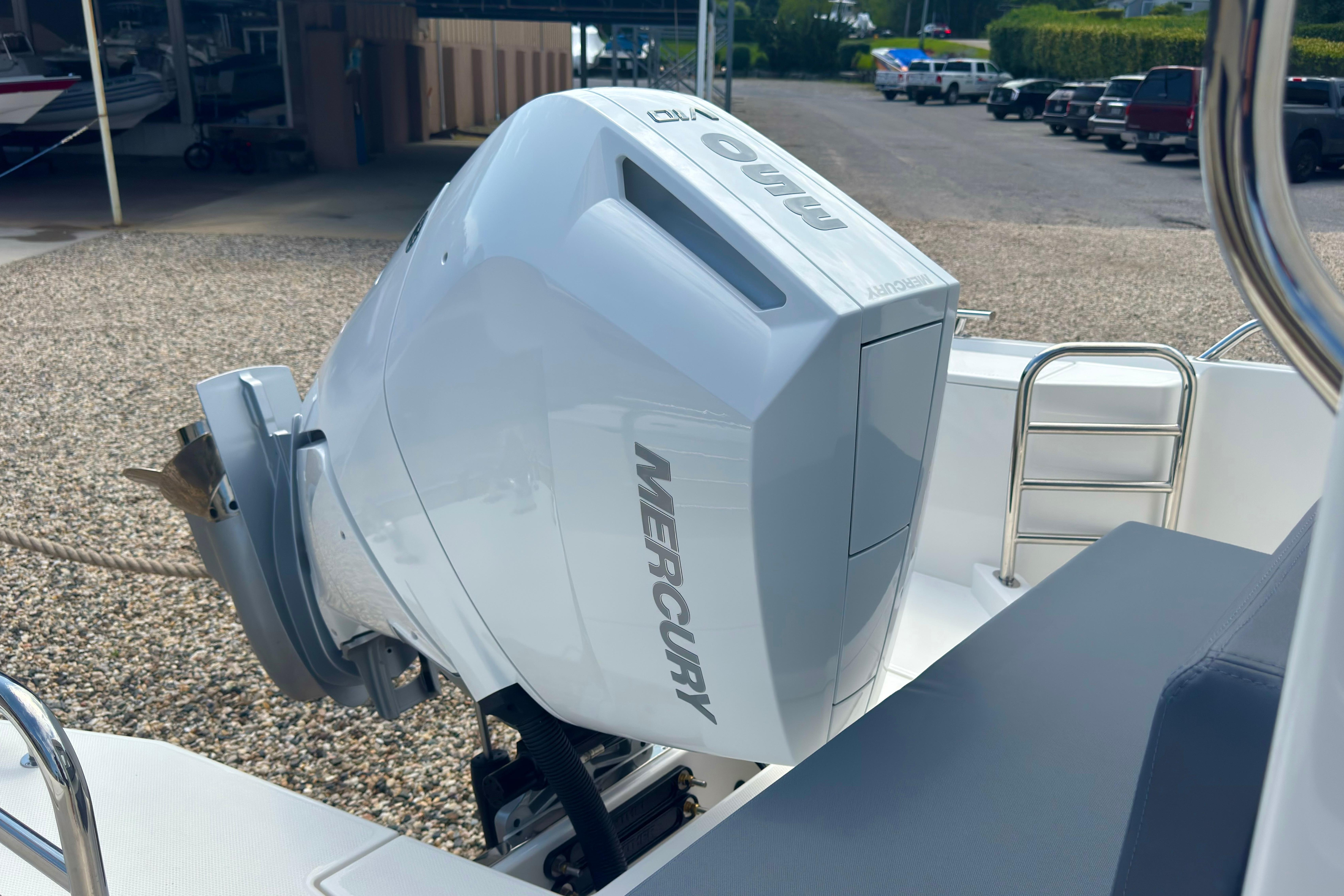 A Mercury outboard motor on a Nimbus Commuter 9 boat, situated on a gravel lot.