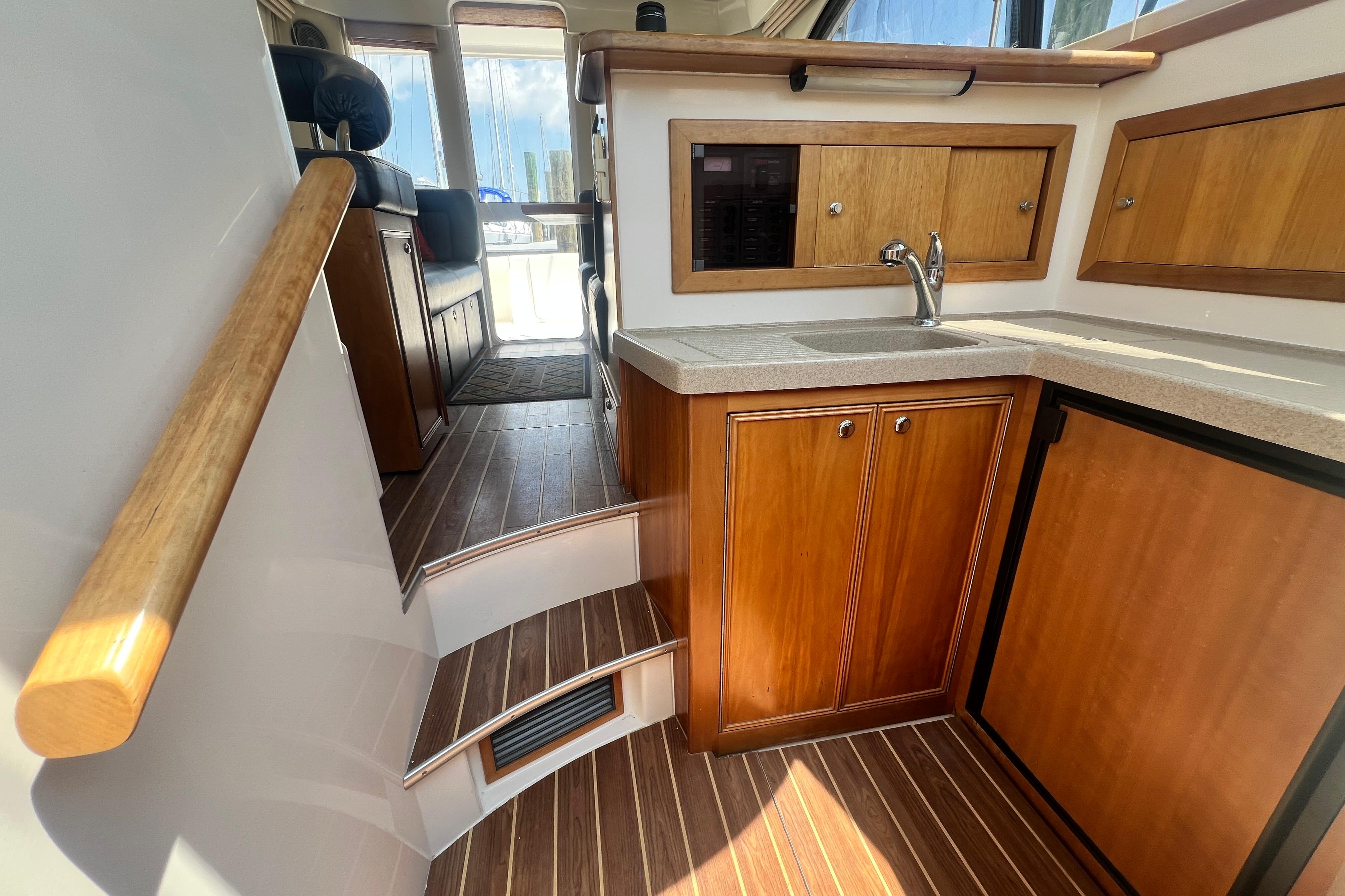 Interior of 2007 Riviera 33 Flybridge yacht with wooden cabinetry and compact kitchen area.