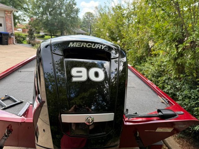 A red boat with a Mercury 90 outboard motor, surrounded by trees.