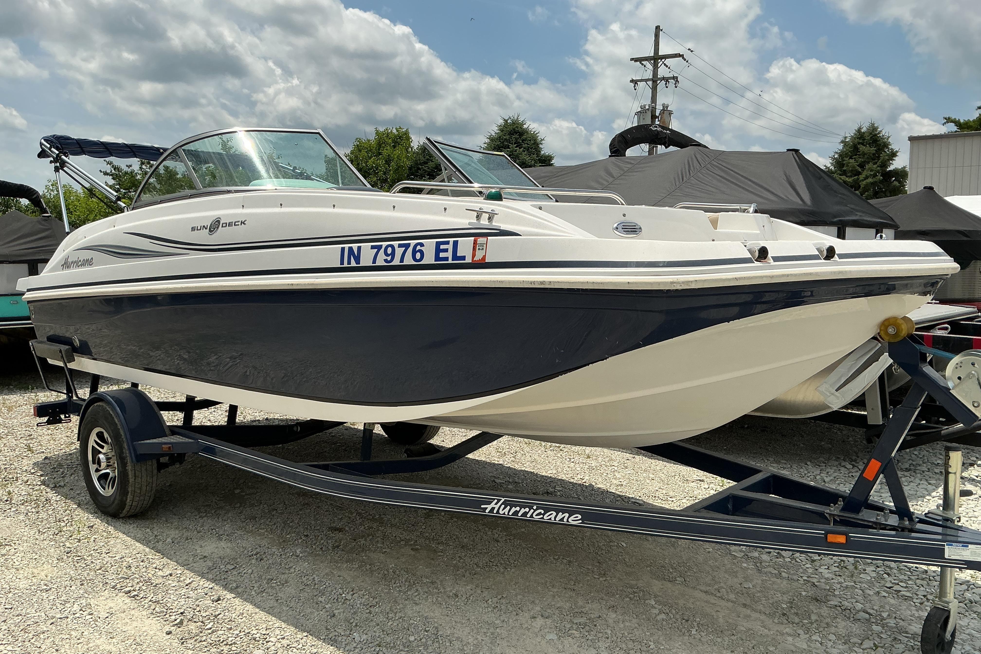 2015 Hurricane SunDeck 187 IO boat on trailer under cloudy sky.