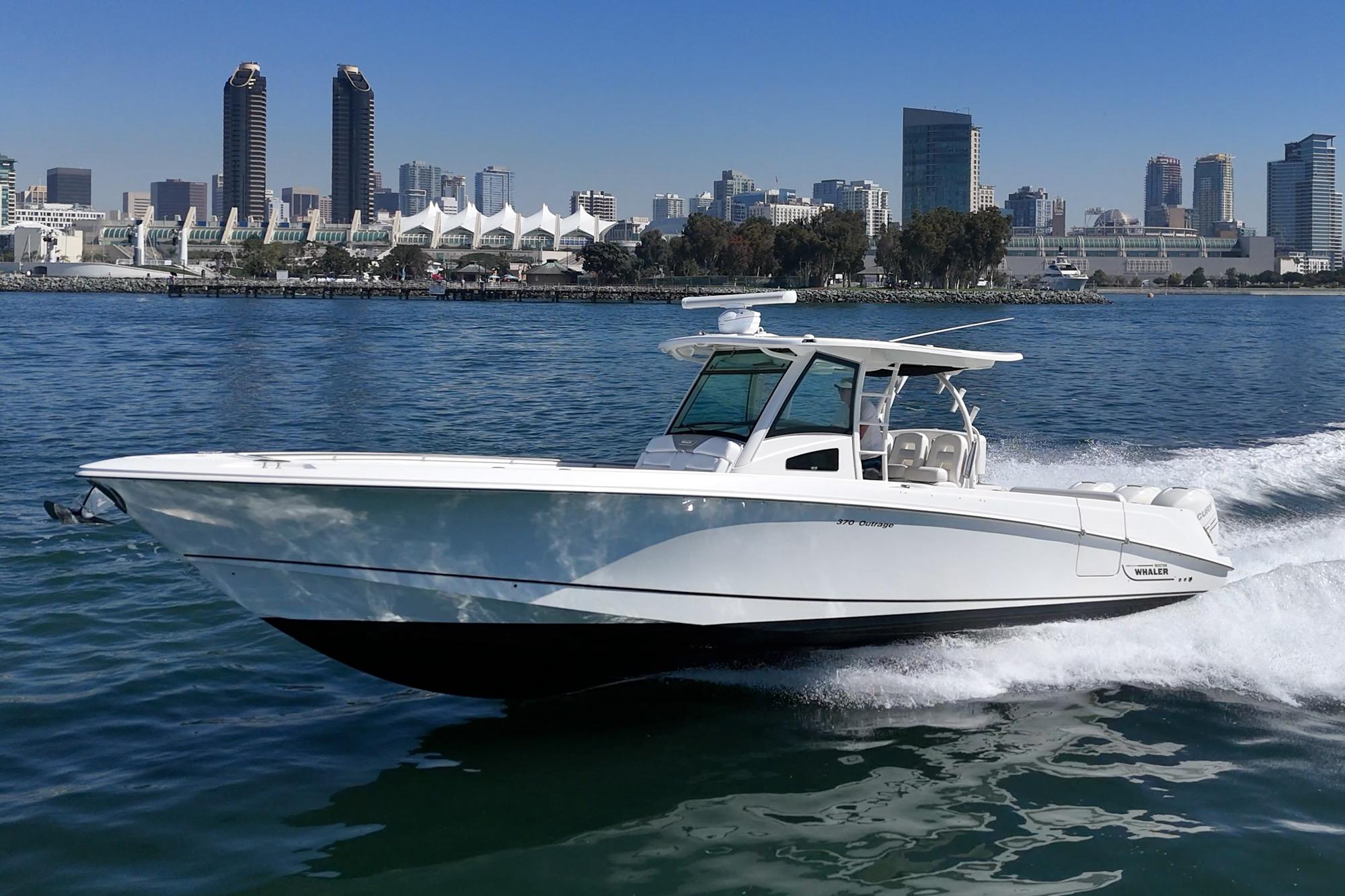 2015 Boston Whaler 370 Outrage cruising on water with city skyline backdrop.