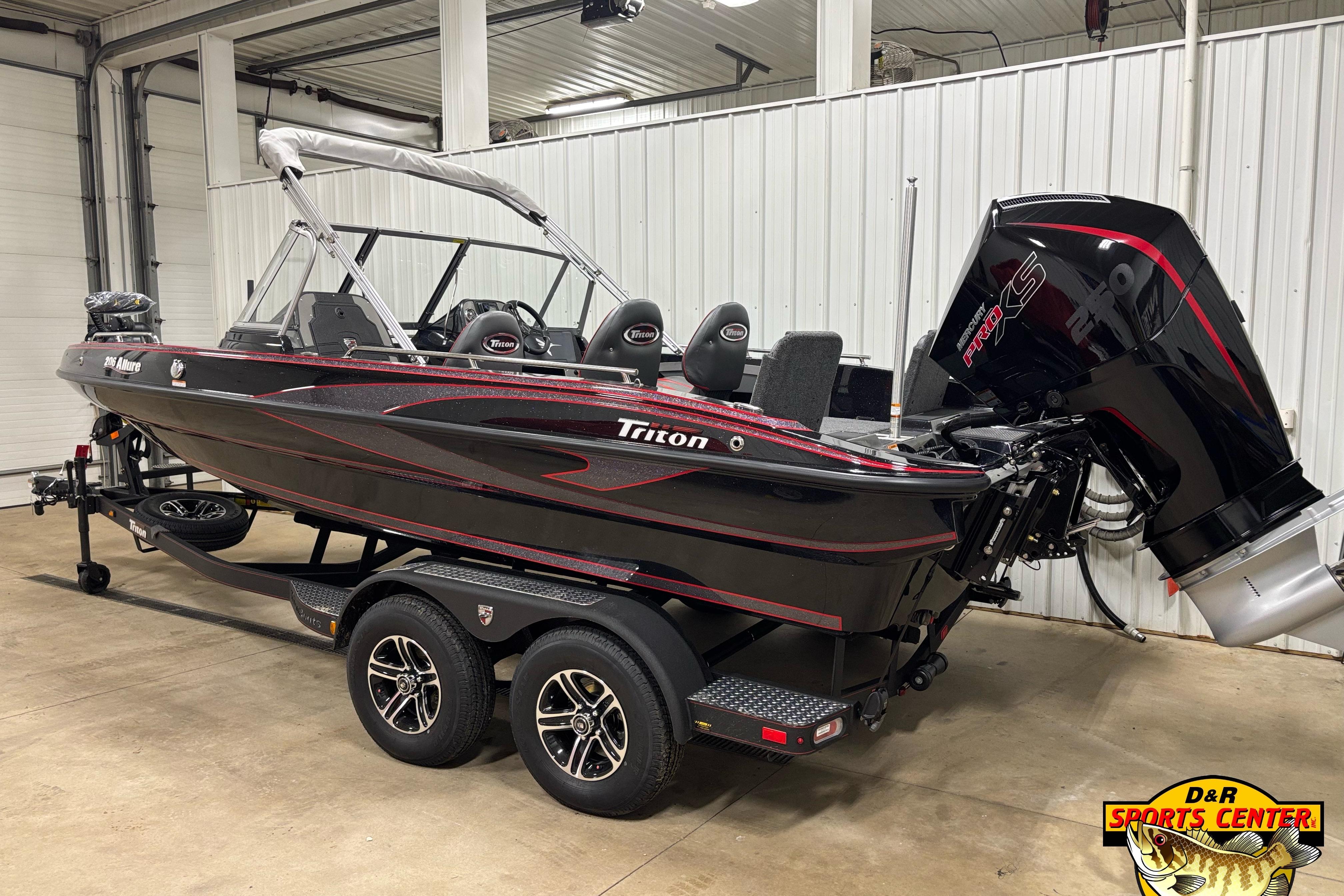 2026 Triton 206 Allure boat with powerful engine, displayed indoors on a trailer.
