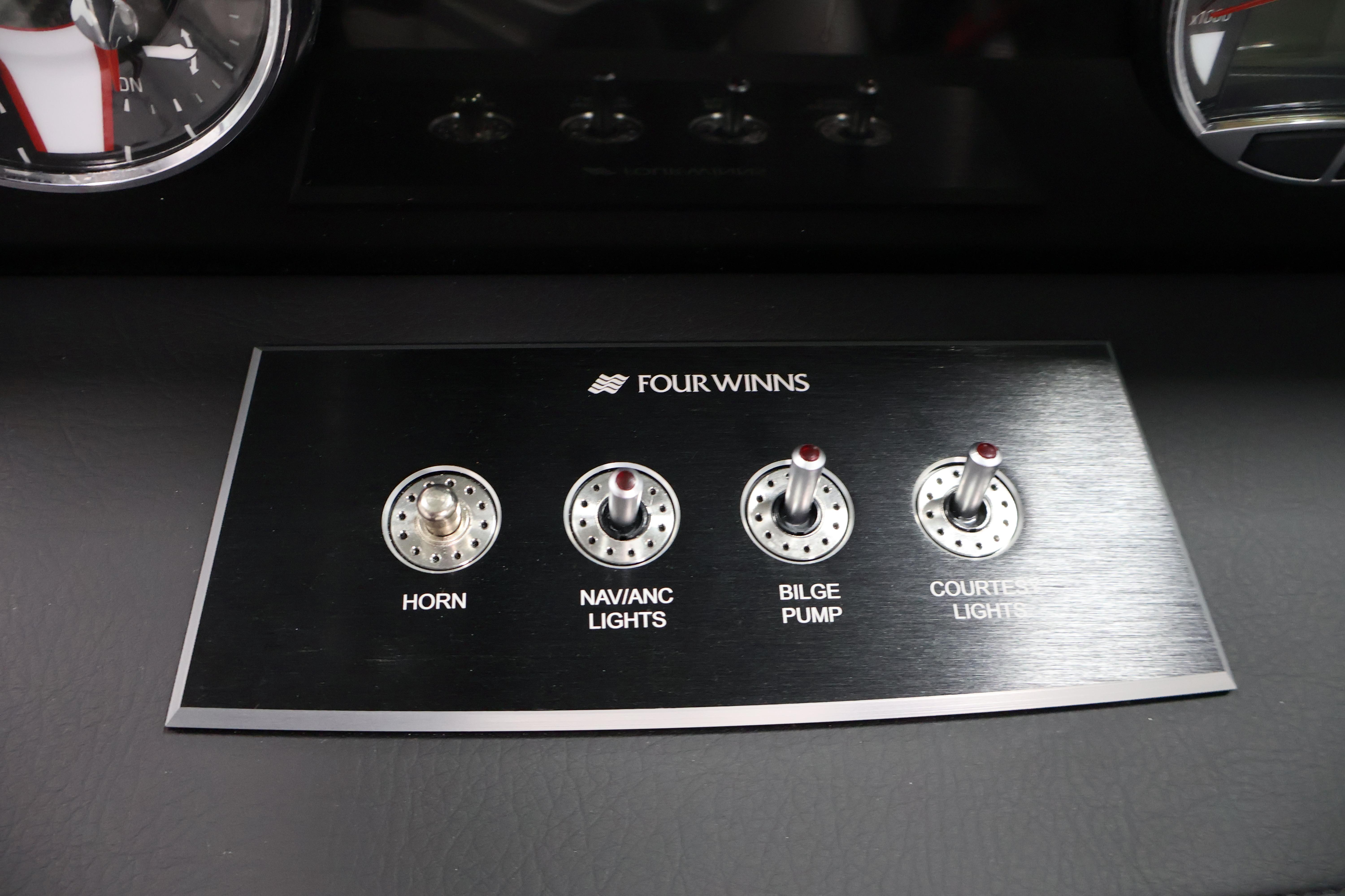 Control panel of 2026 Four Winns H4 Freedom boat with switches for horn, lights, and pump.