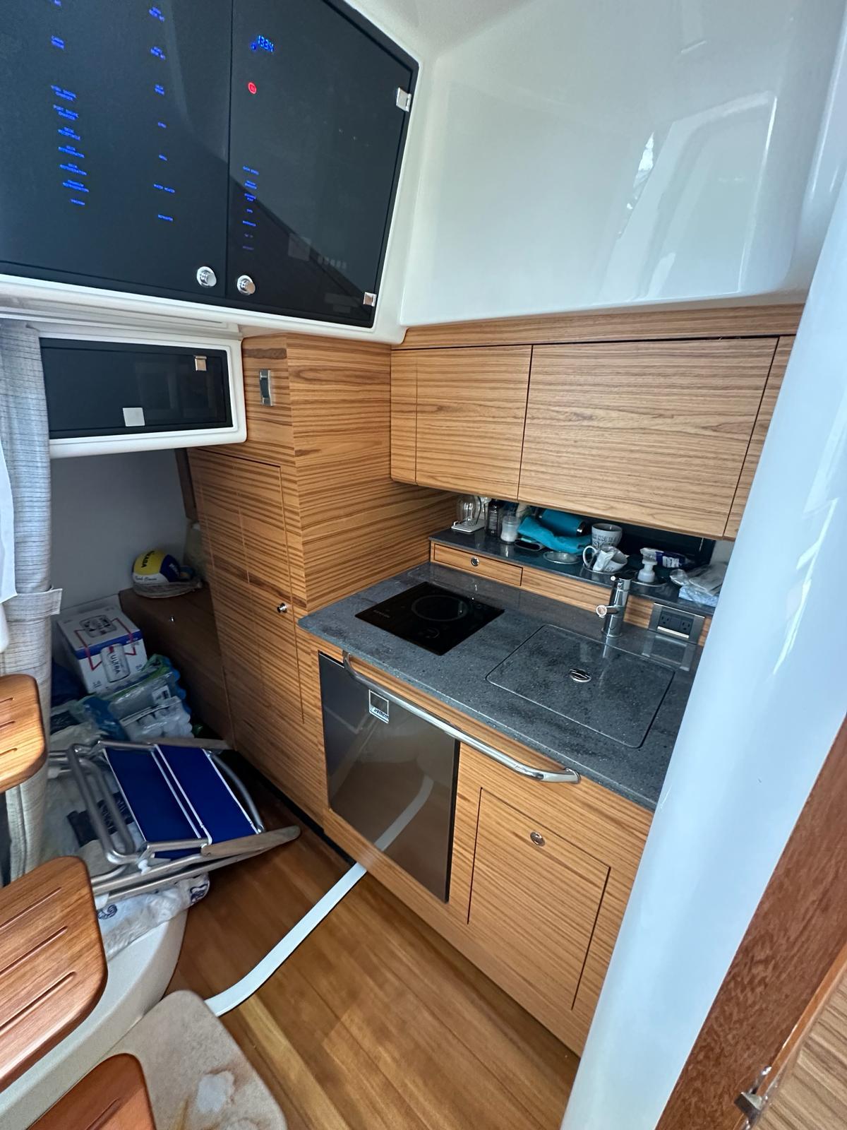 2021 Boston Whaler 405 Conquest kitchen with wood cabinetry and modern appliances.