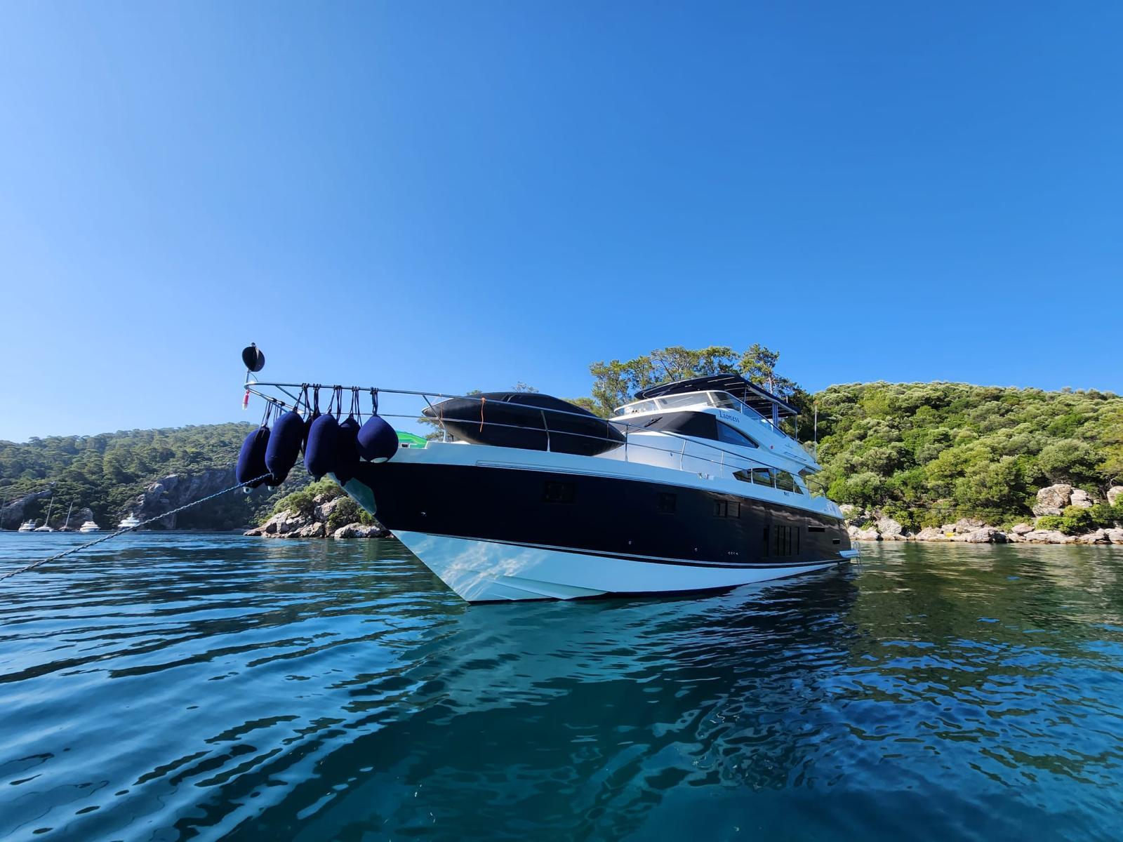 Luxury Fairline Squadron 65 yacht from 2012 on serene blue waters, surrounded by lush greenery.