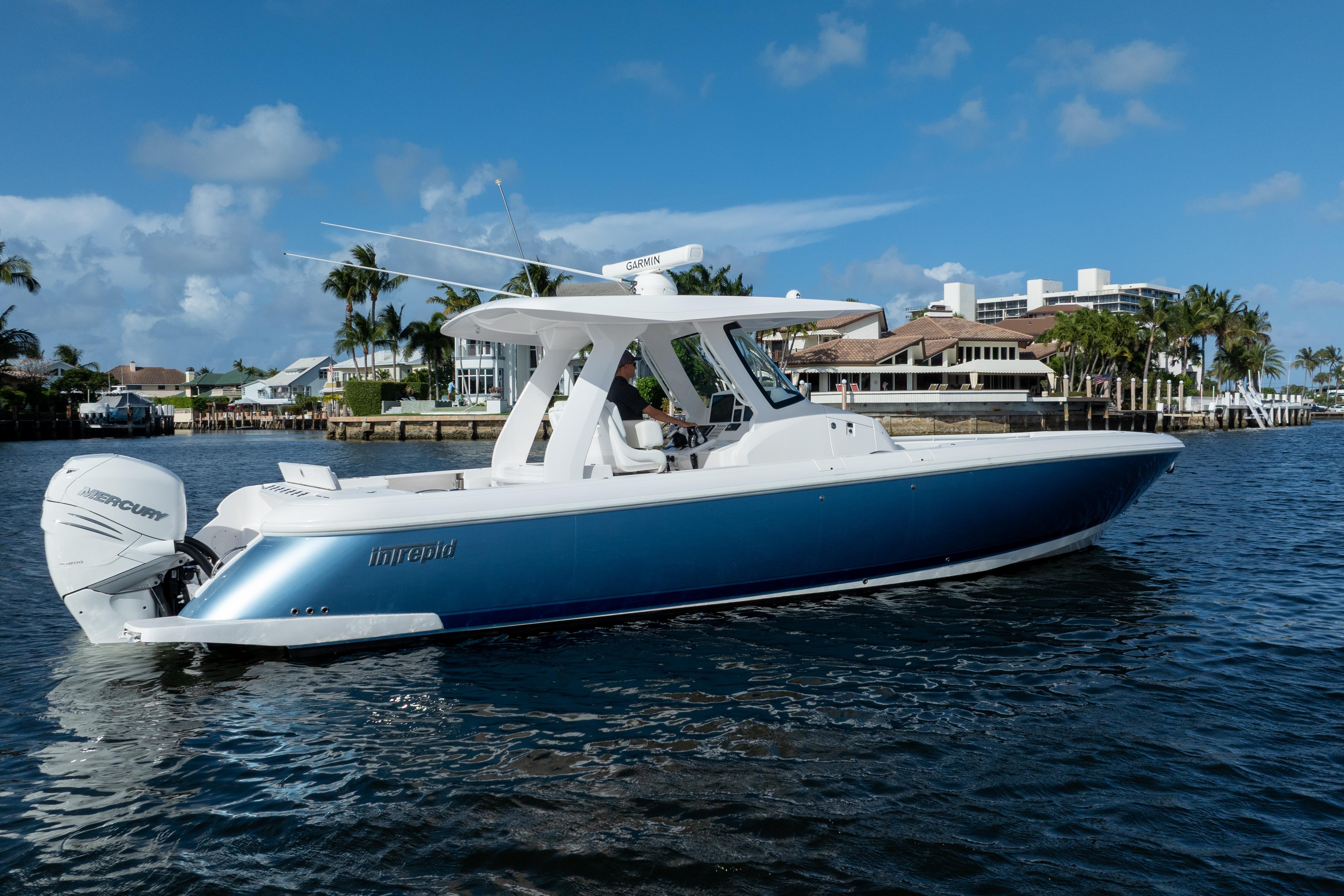 2022 Intrepid 345 Nomad SE boat on water, with blue hull and twin Mercury engines.