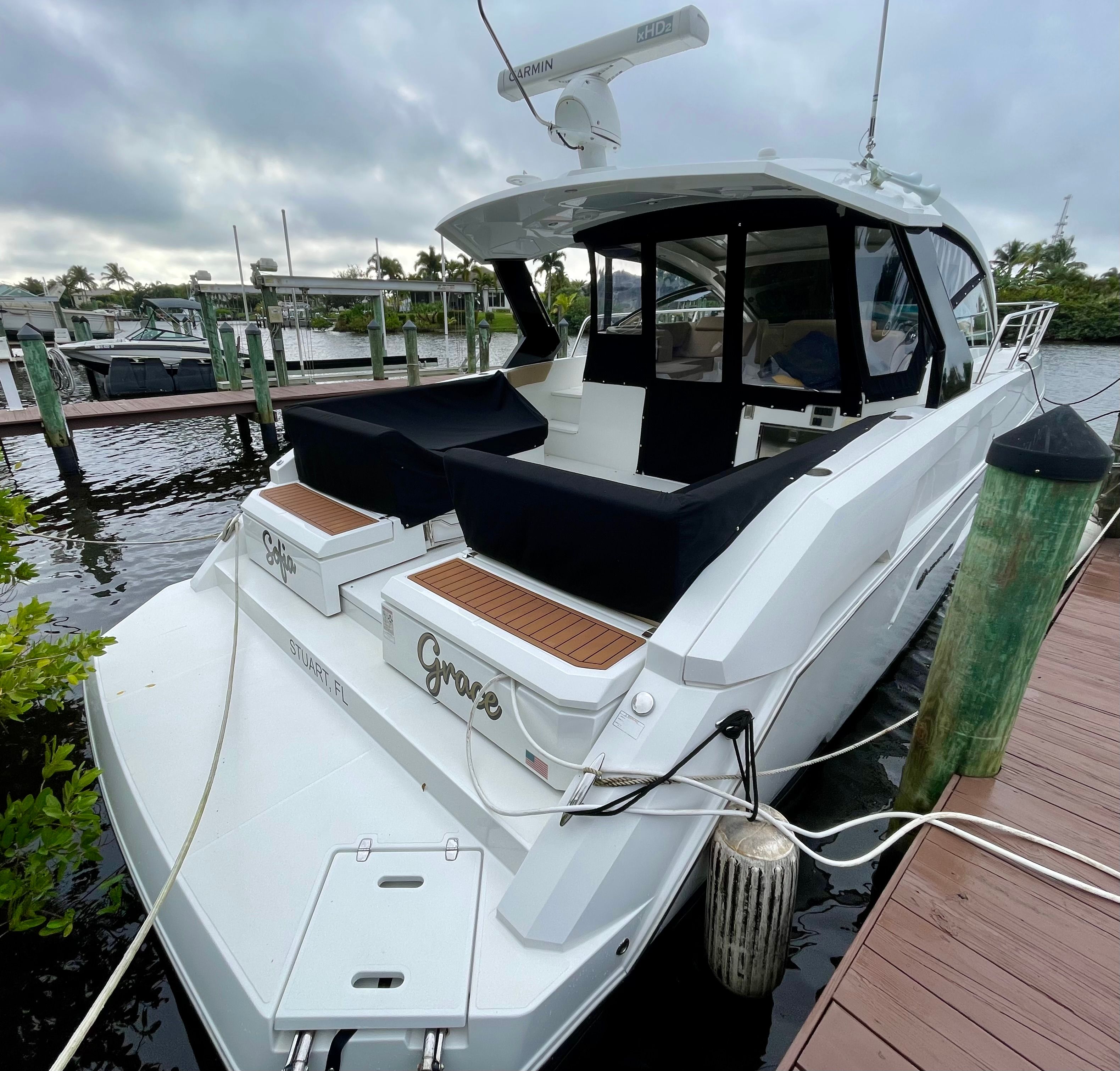 A luxurious white yacht docked, featuring black seating and wooden accents.
