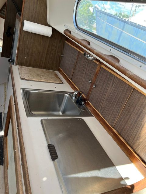 Interior view of a 1969 Morgan 30 with a small kitchen, sink, and wood paneling.