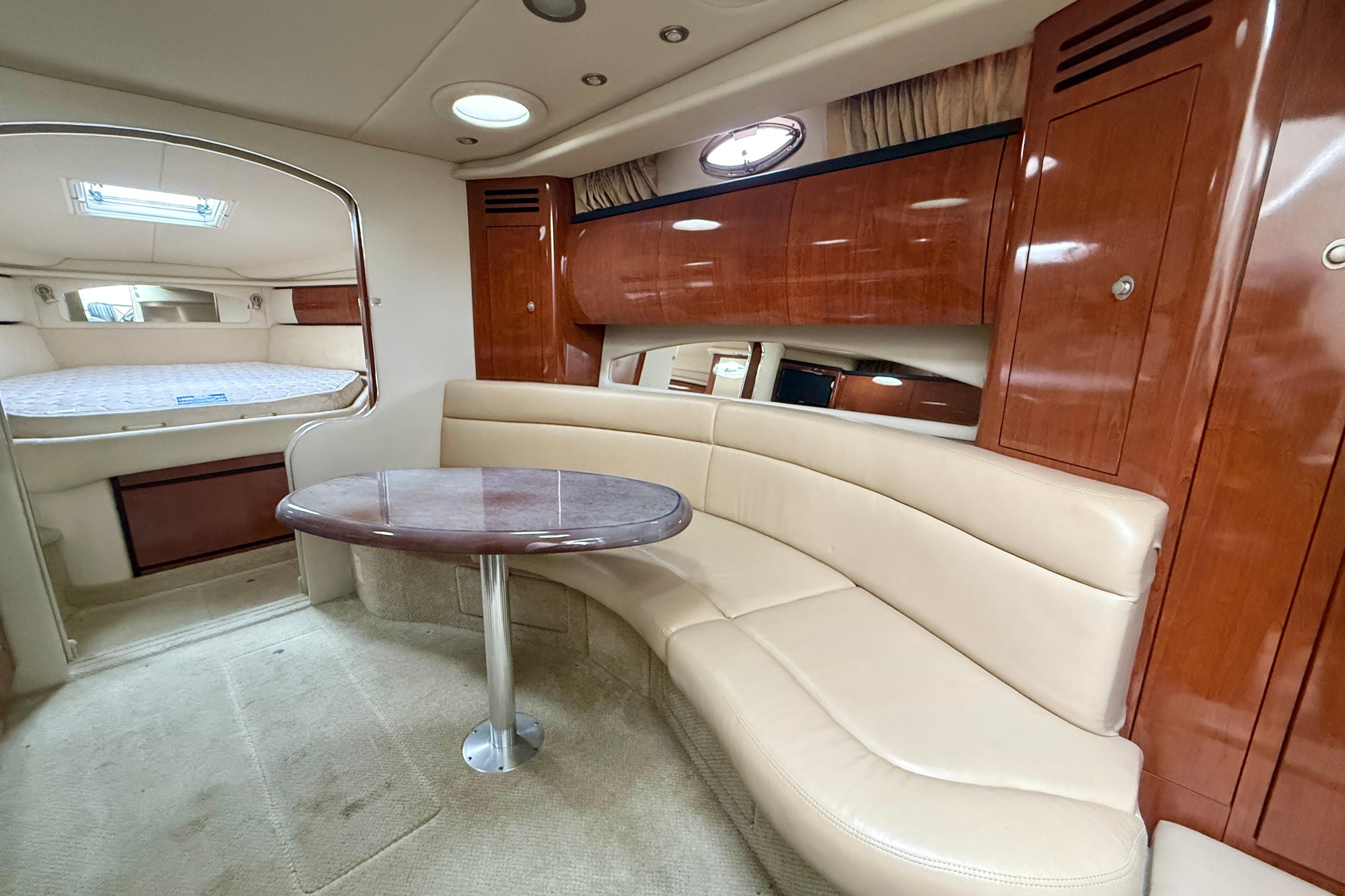 Interior of 2004 Searay 360 Sundancer yacht with beige seating and wooden cabinetry.