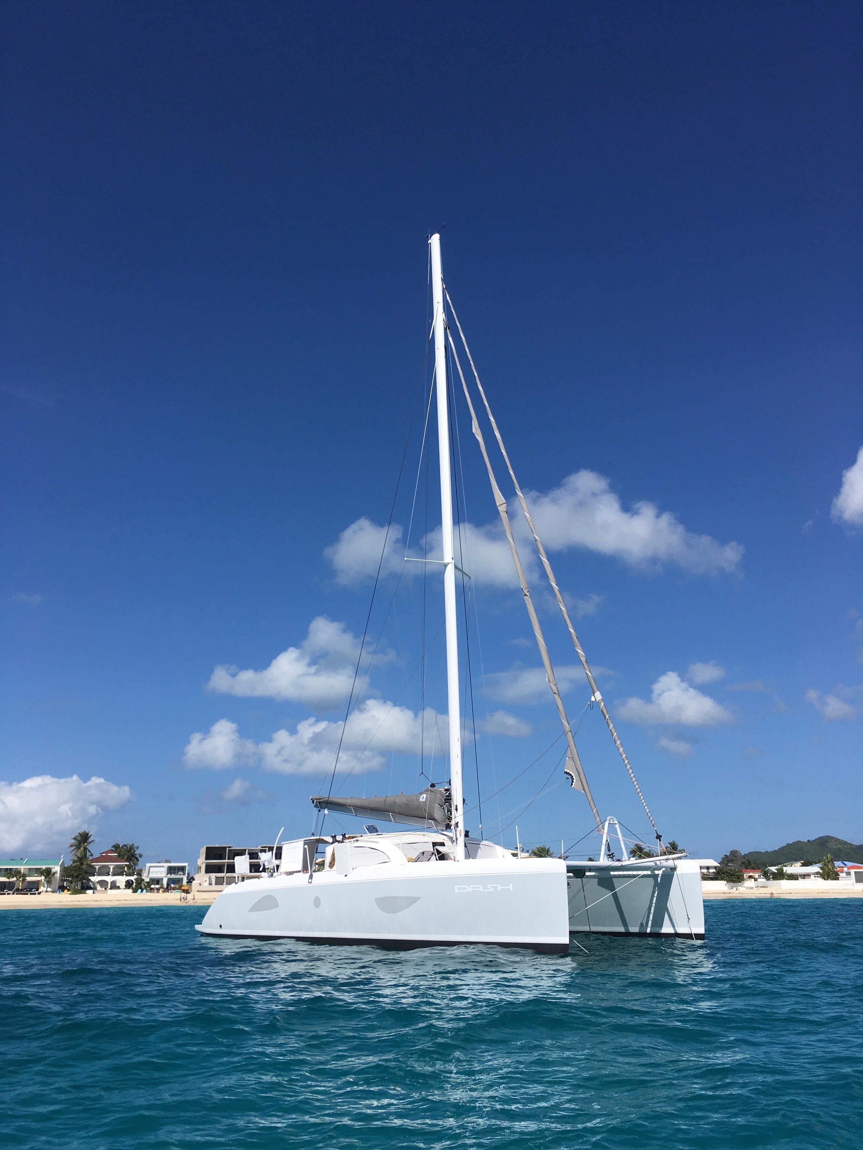 2010 Outremer 49 catamaran sailing on clear blue waters under a sunny sky.