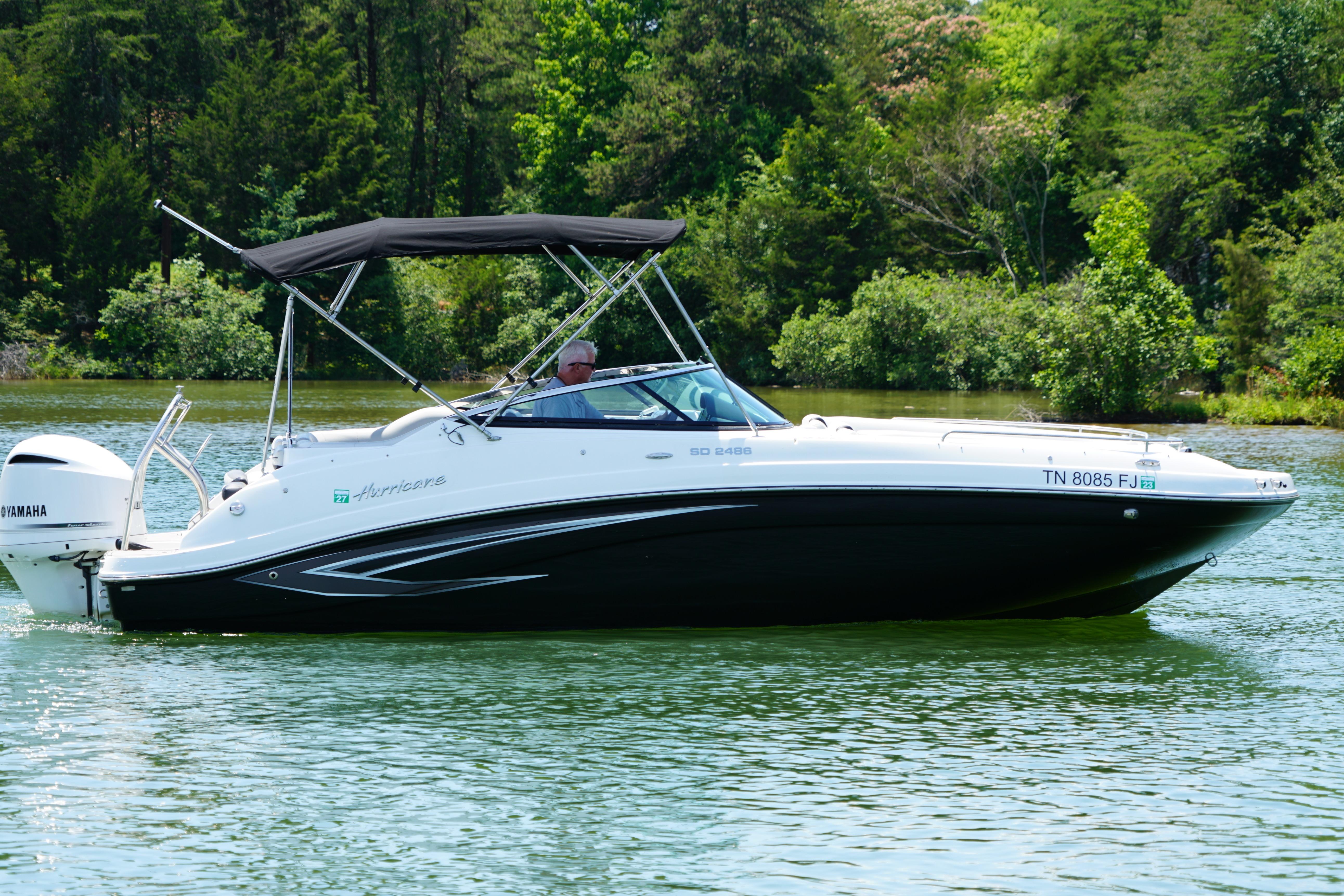 2020 Hurricane SunDeck 2486 OB boat cruising on a scenic lake.