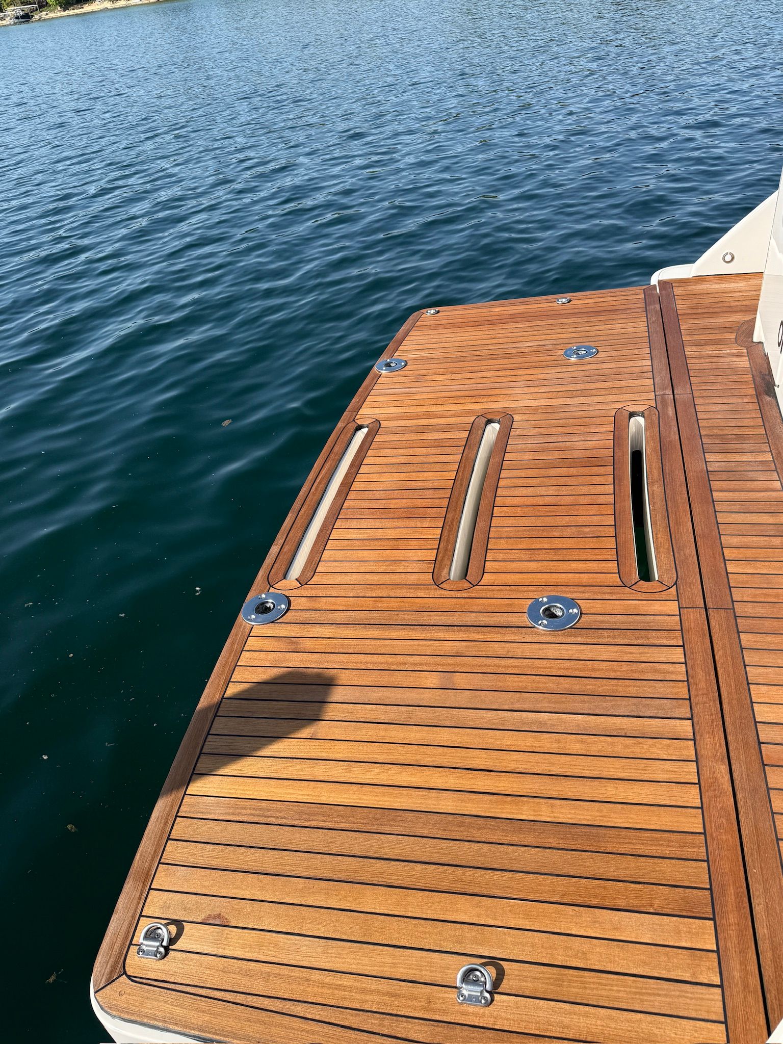Teak platform of a 2017 Tiara Yachts C44 Coupe on calm water.