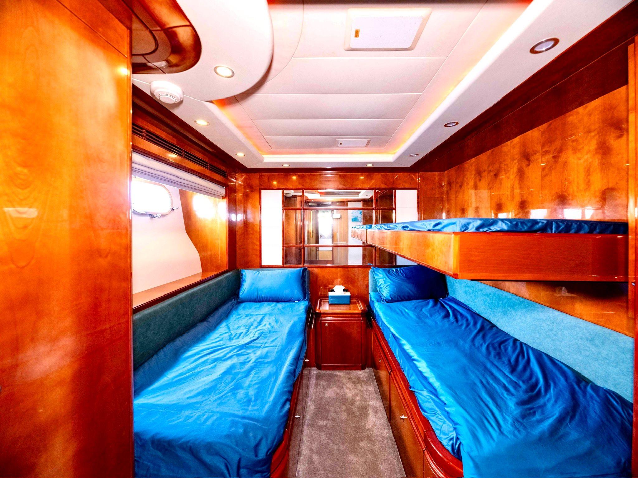 Luxurious cabin interior of 2005 Ferretti Yachts Custom Line 112 with wooden finish and blue bedding.