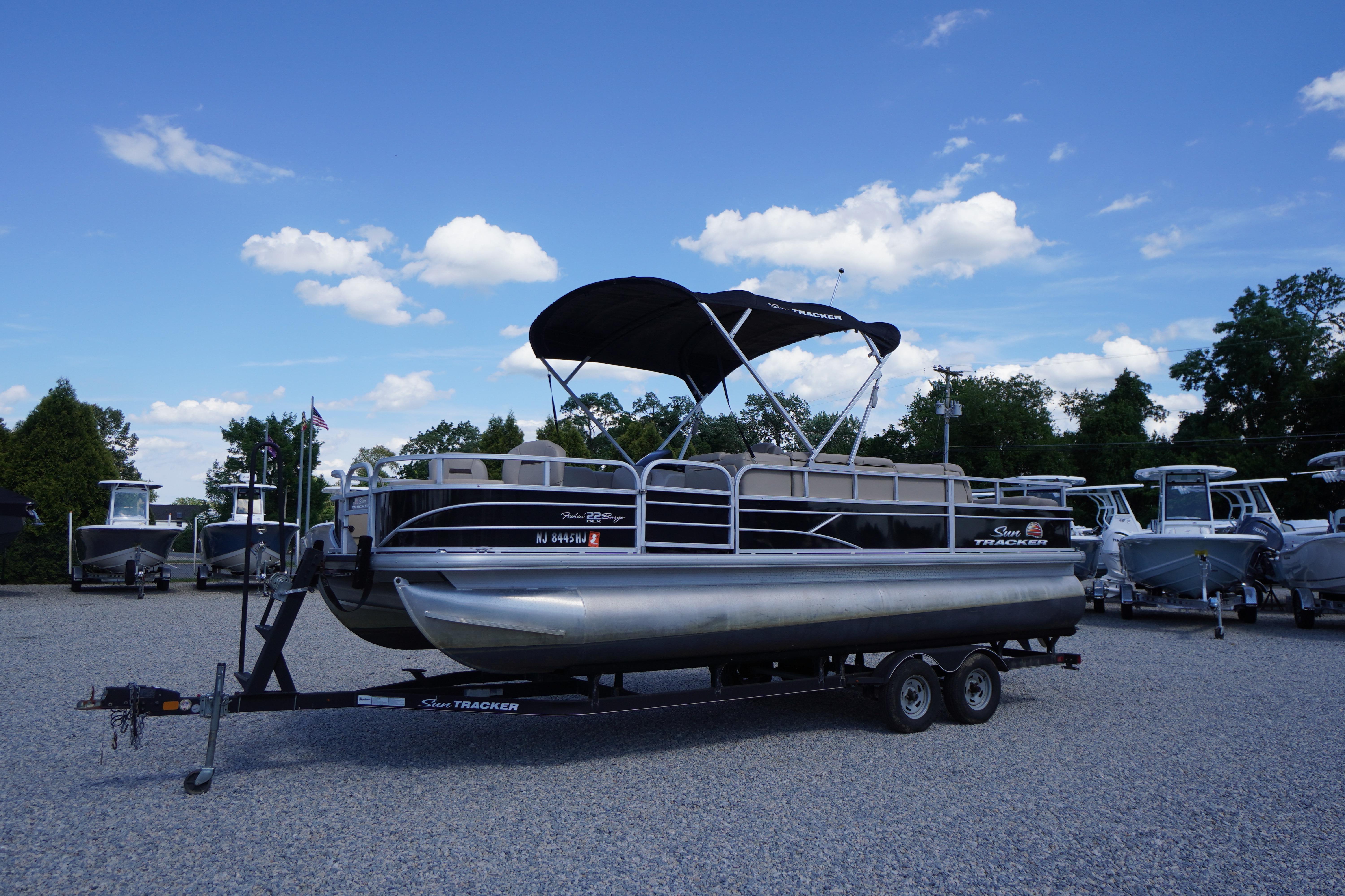 2019 SUNTRACKER Fishin' Barge 22 DLX pontoon boat on trailer, parked outdoors.
