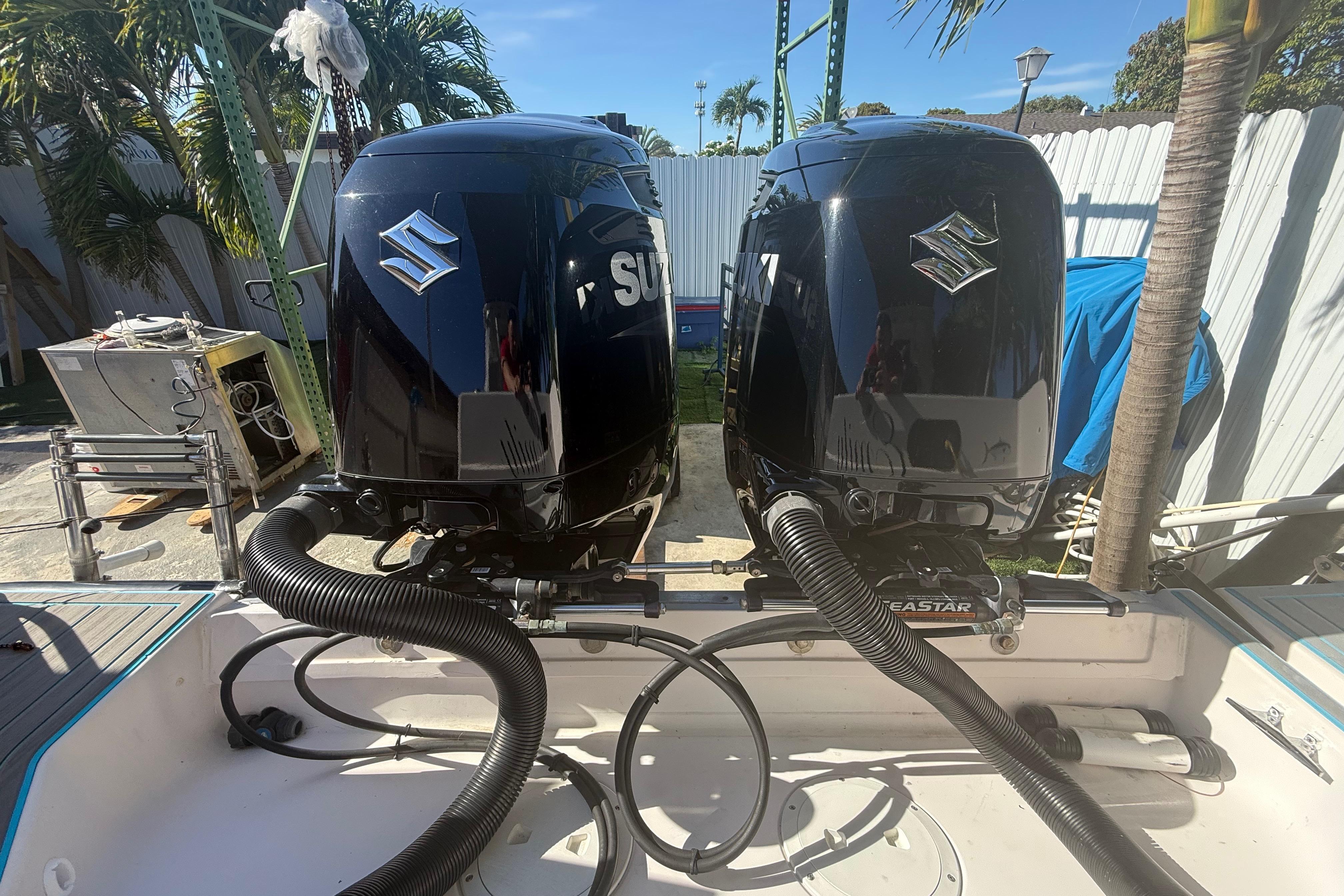 Twin Suzuki outboard motors on a 1996 Grady-White Sailfish 272 boat, docked outdoors.