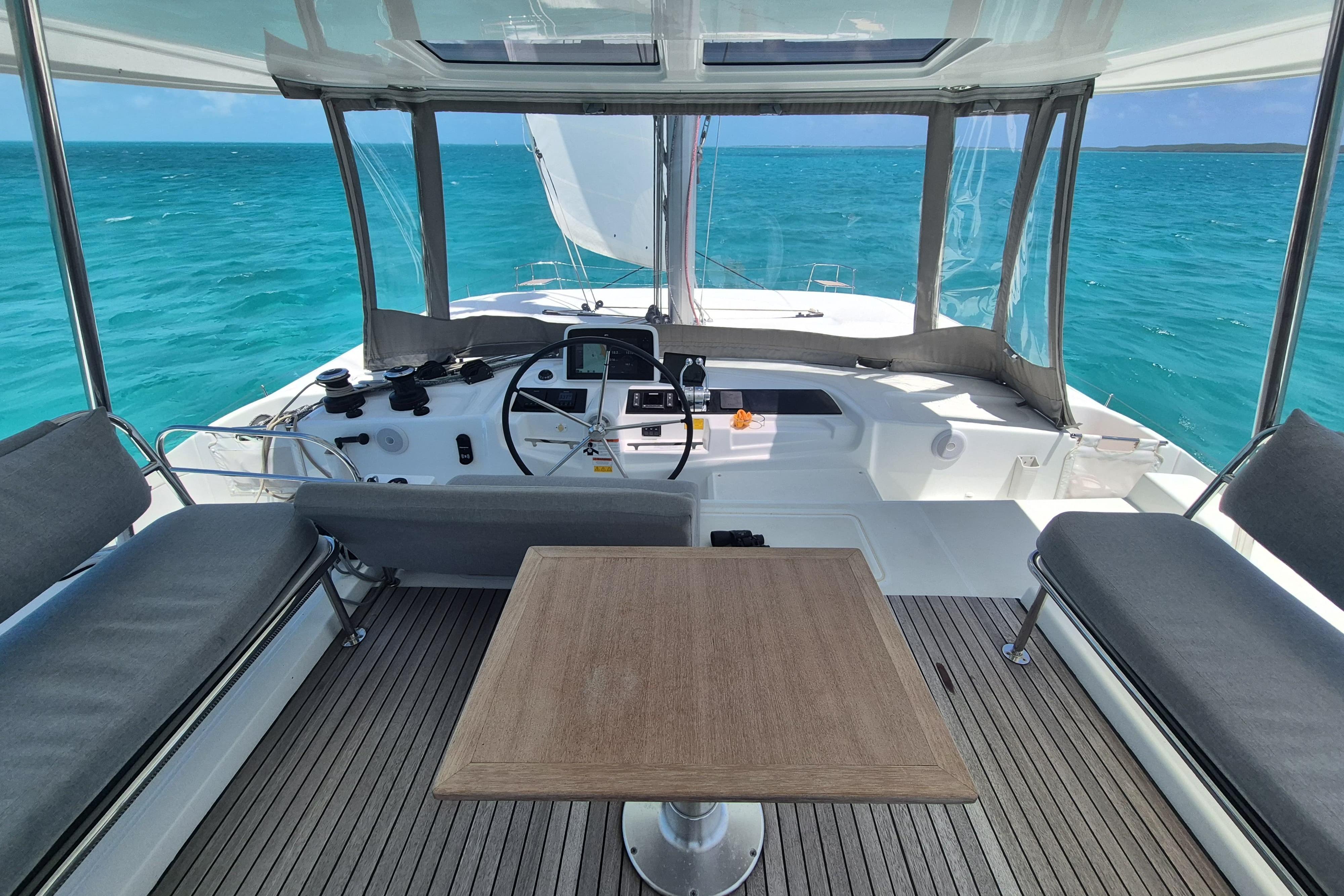 Cockpit view of 2025 Lagoon 46 catamaran with ocean backdrop and seating area.