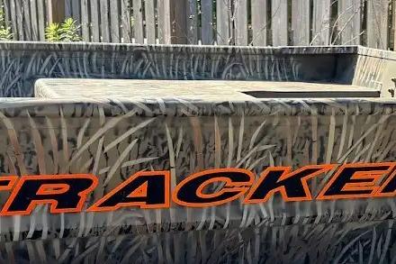 2026 Tracker Grizzly 15 Jon boat with camouflage design and bold orange lettering.