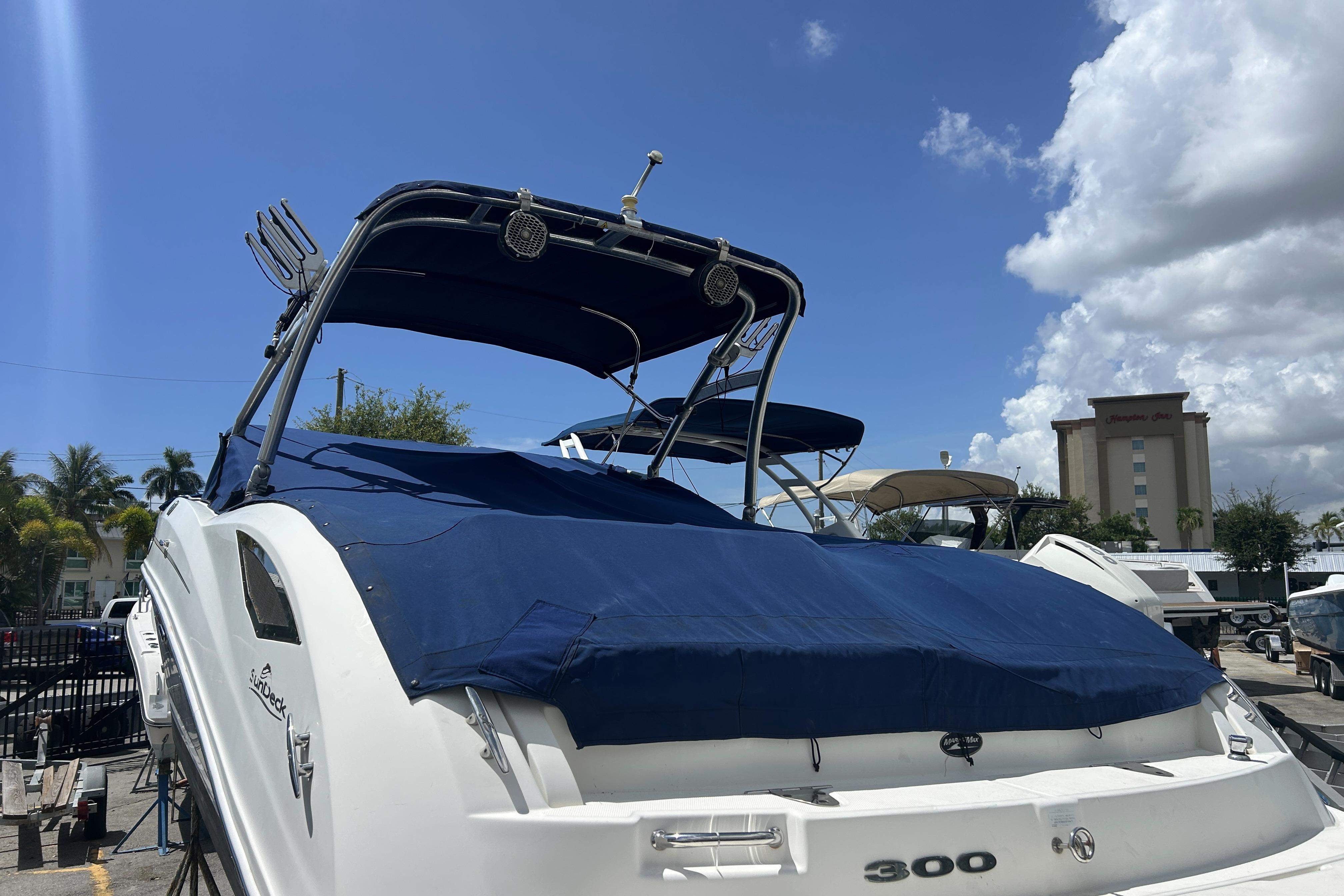 2011 Sea Ray 300 Sundeck boat with blue cover, docked under a clear sky.