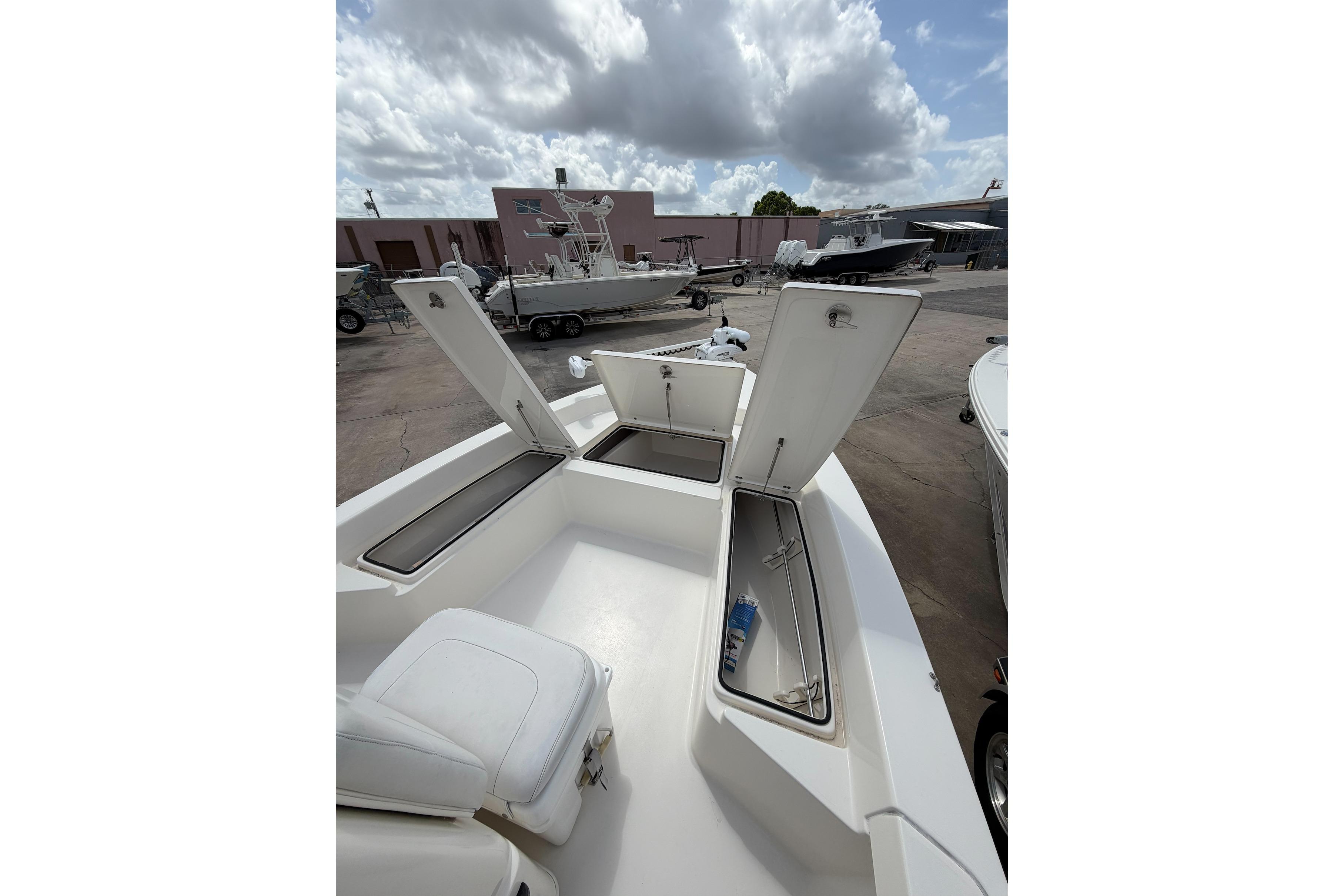 2017 Pathfinder 2200 TRS boat with open storage compartments, docked under cloudy sky.