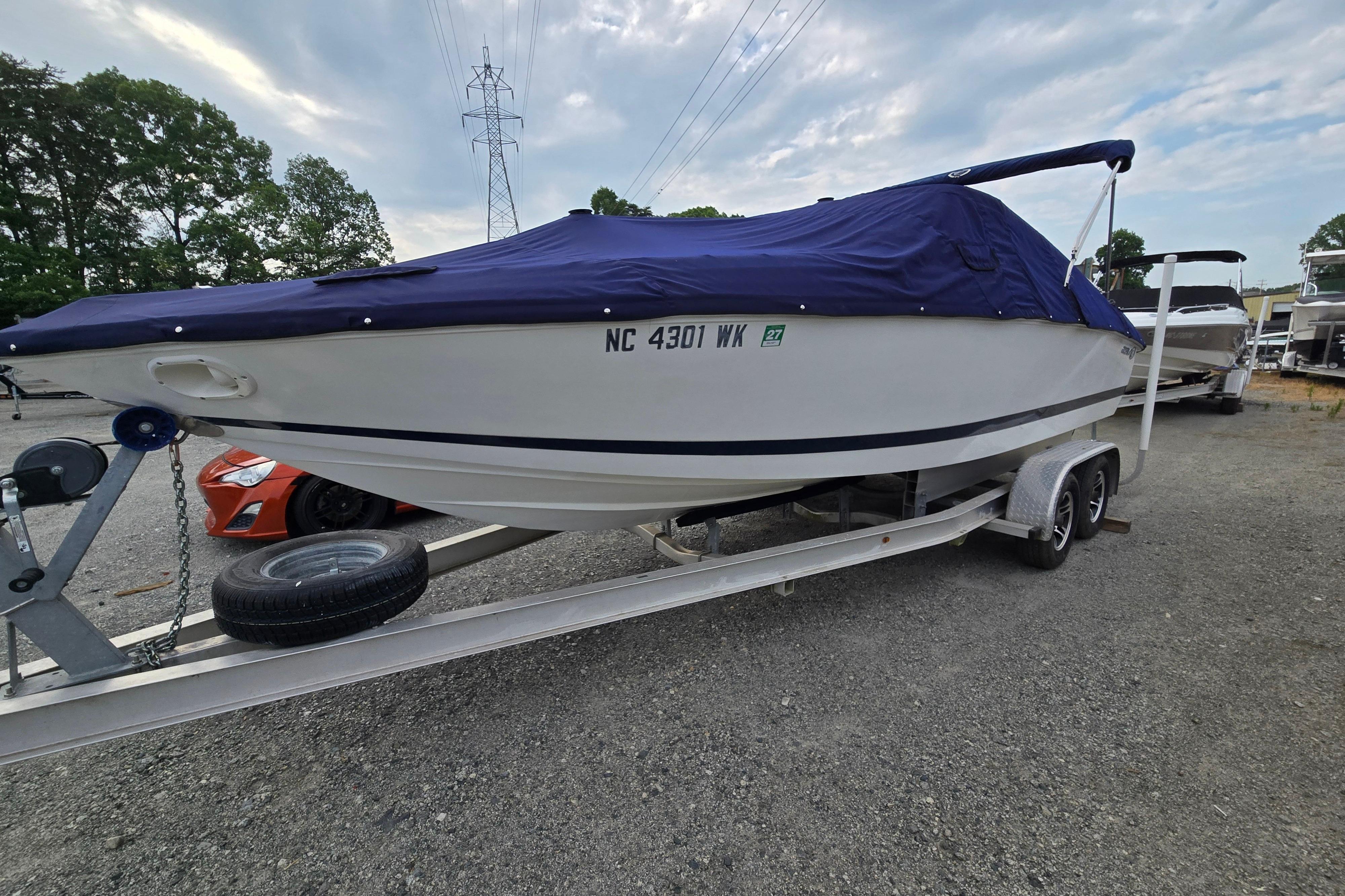 2000 Cobalt 246 boat on trailer with blue cover, parked outdoors.