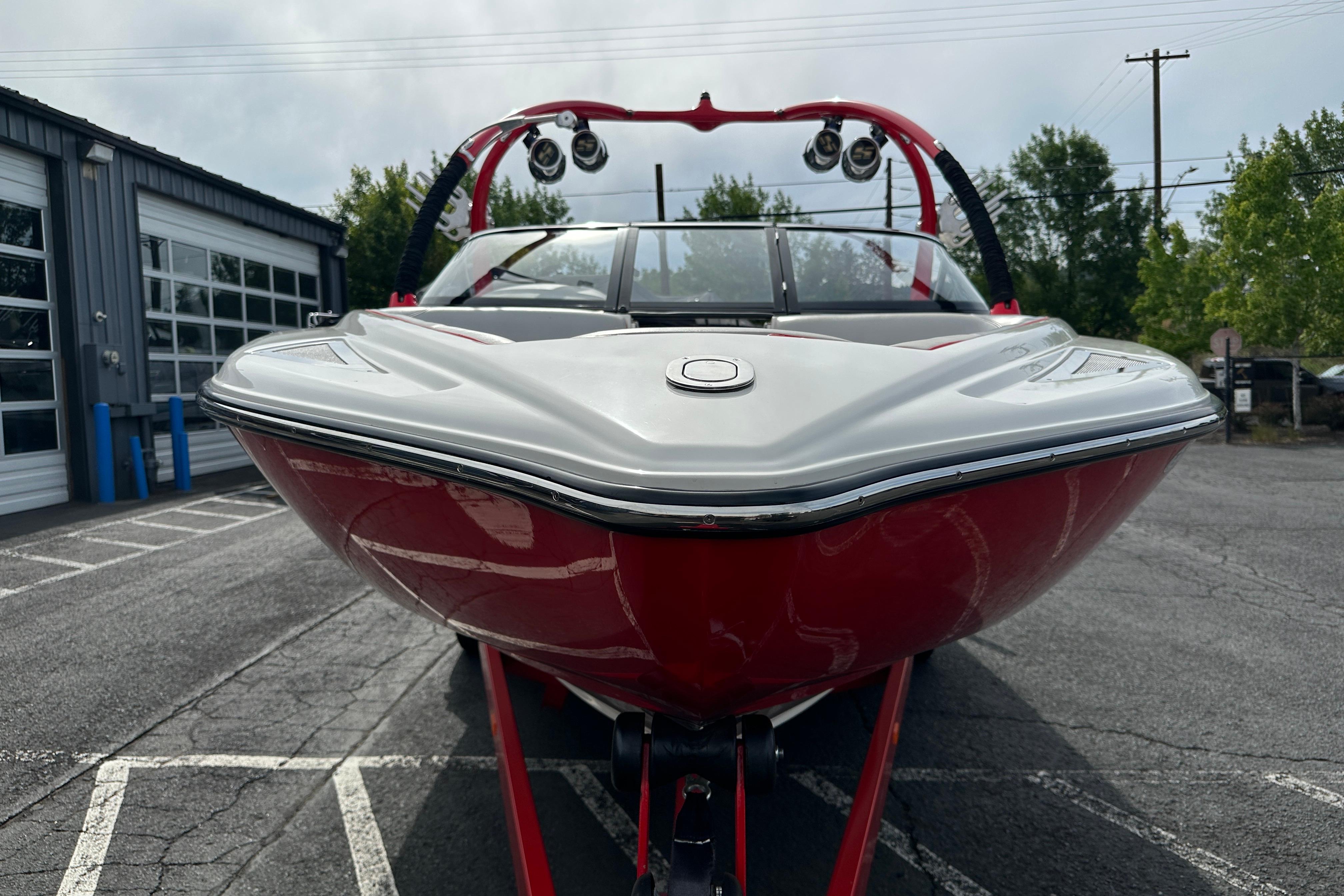 2008 Centurion Enzo SV240 boat, red and white, parked outdoors near a garage.