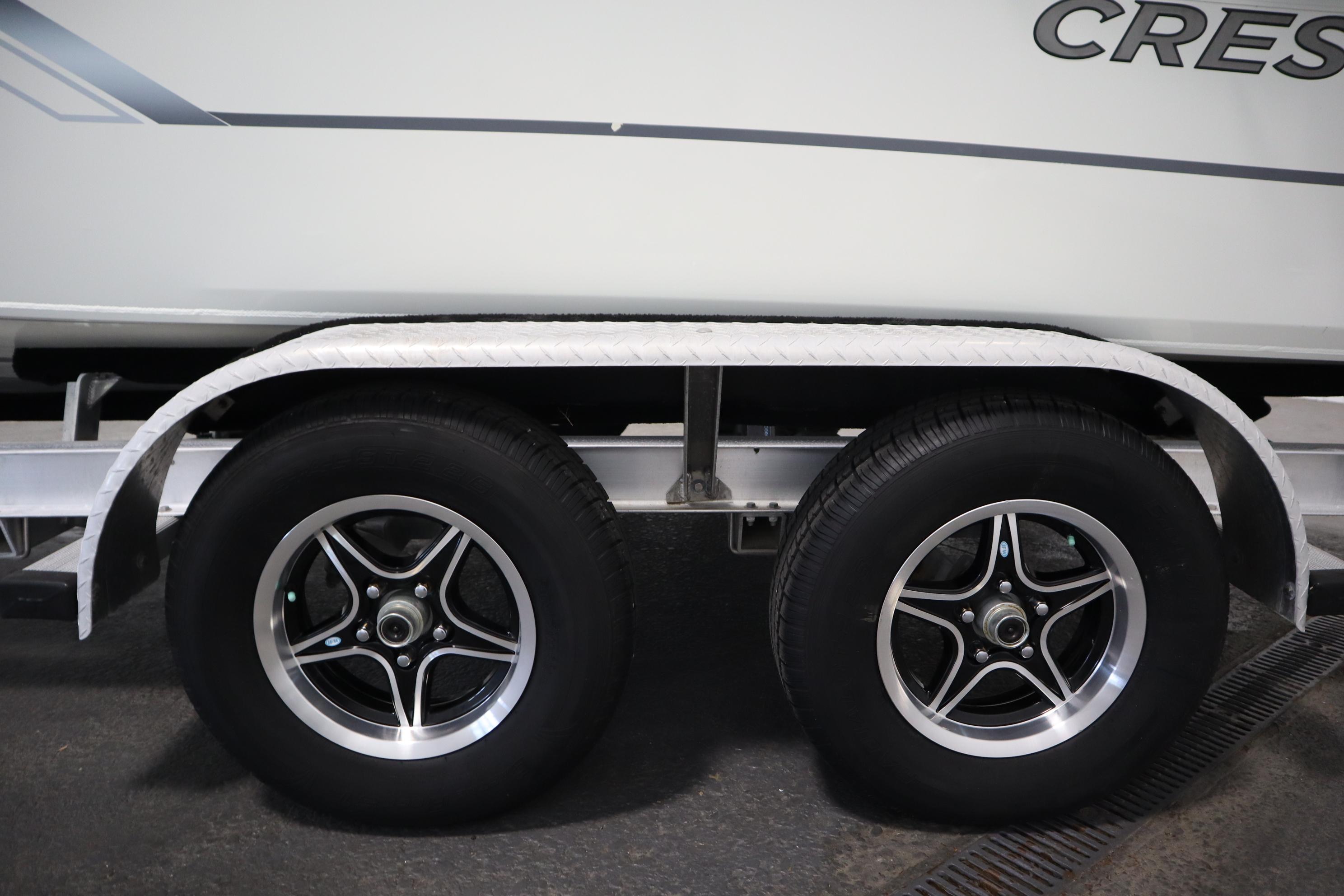 Close-up of a boat trailer with two tires and part of the boat hull.