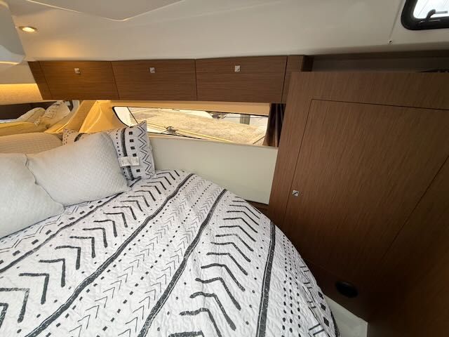 Interior of the Jeanneau NC 1095 with cozy bed and wooden cabinets.