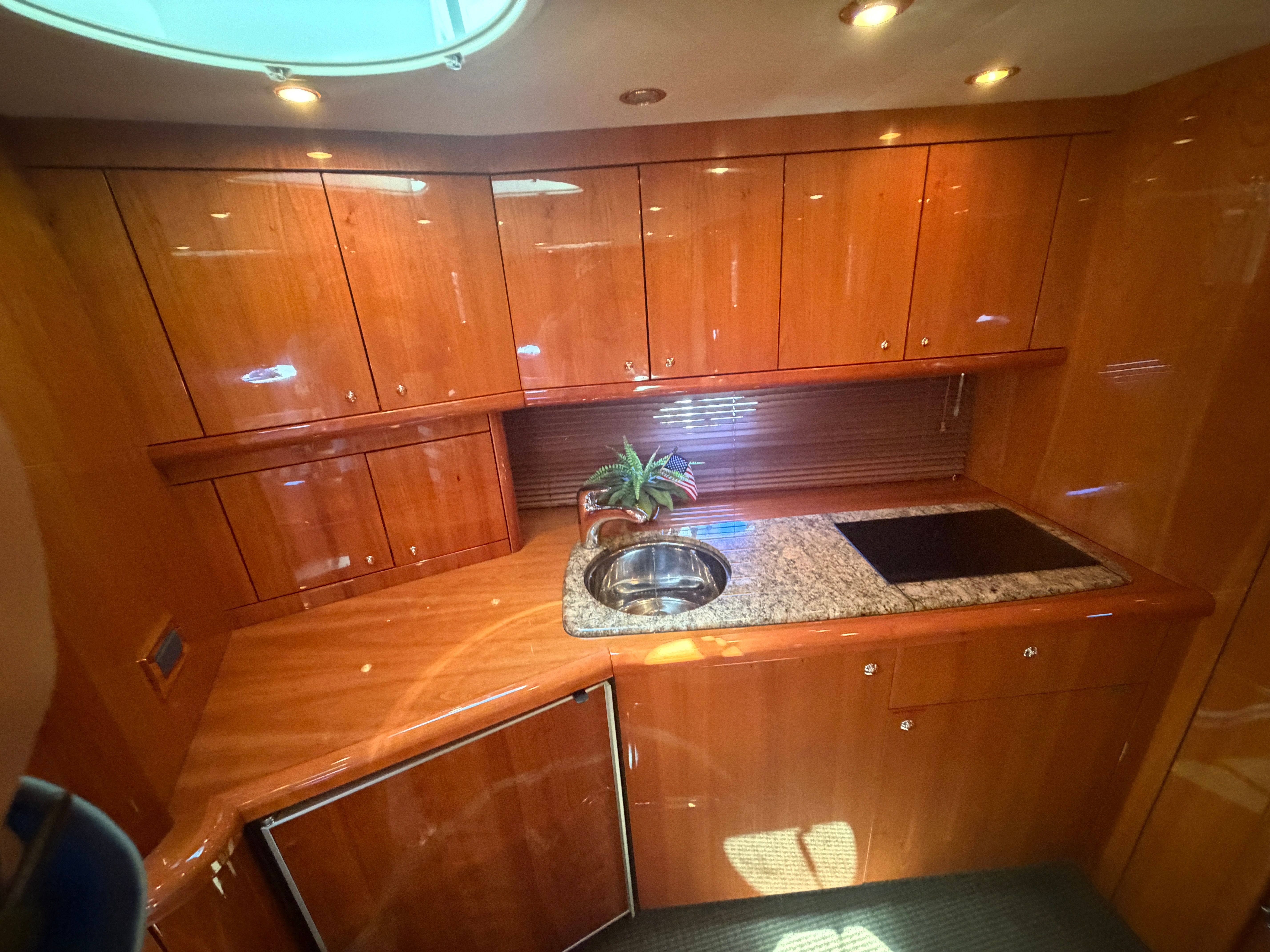The 2008 Sunseeker Portofino 53 kitchen features glossy wood cabinets, a sink, and a stove.