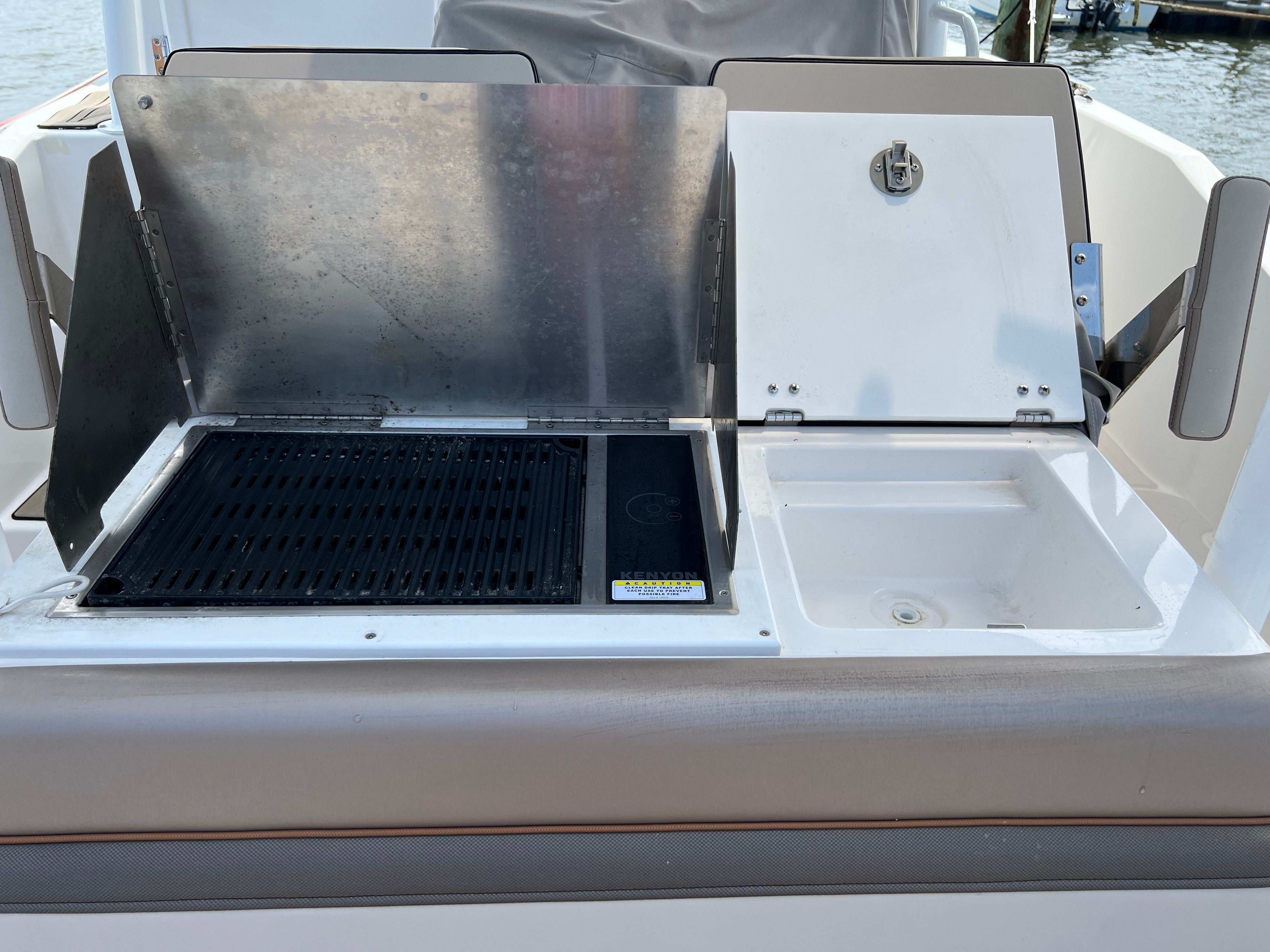 The image shows an outdoor kitchen on a boat with a grill and sink.