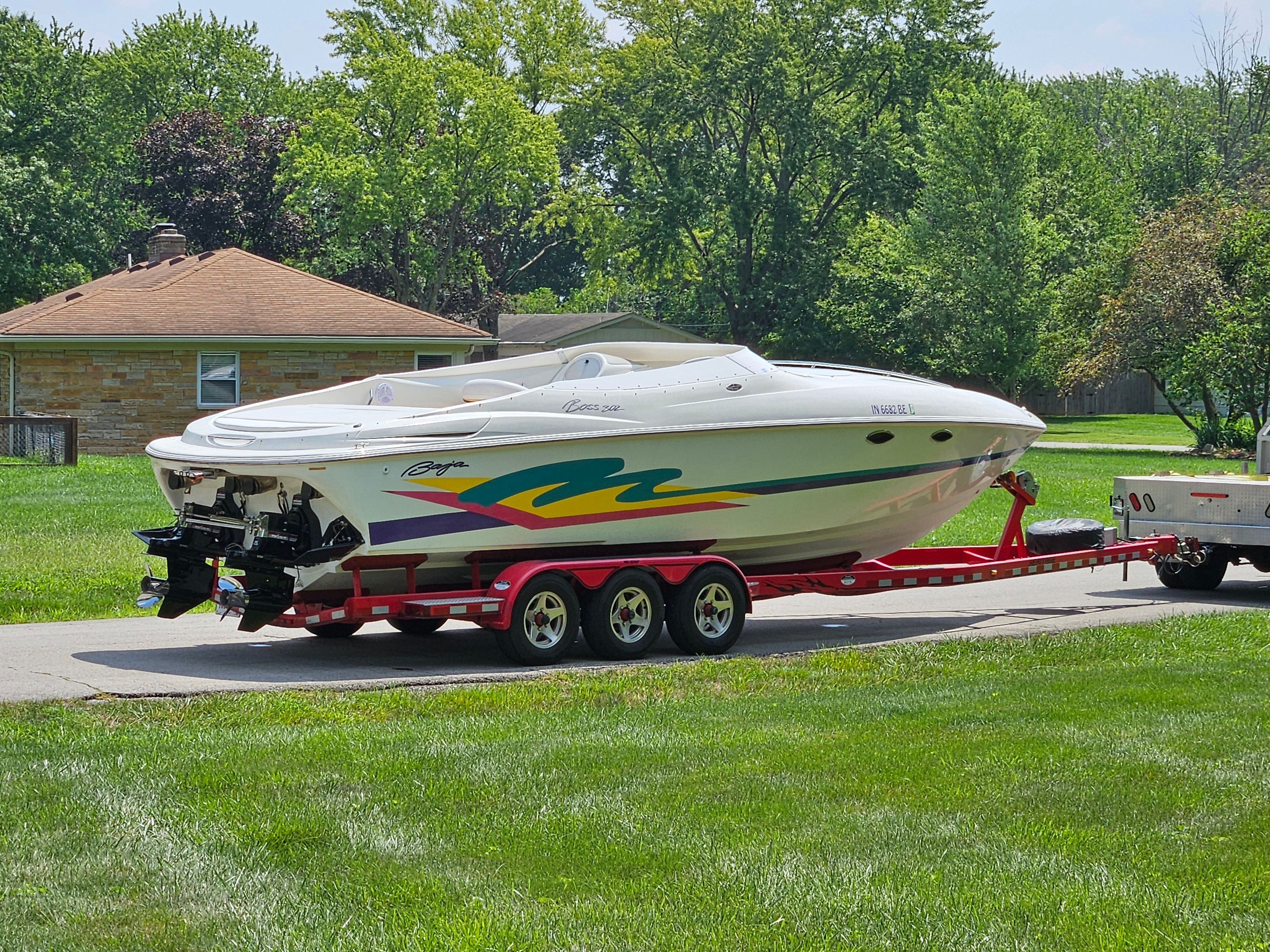 A 1996 Baja 302 Boss on a trailer, parked on a road next to a house.