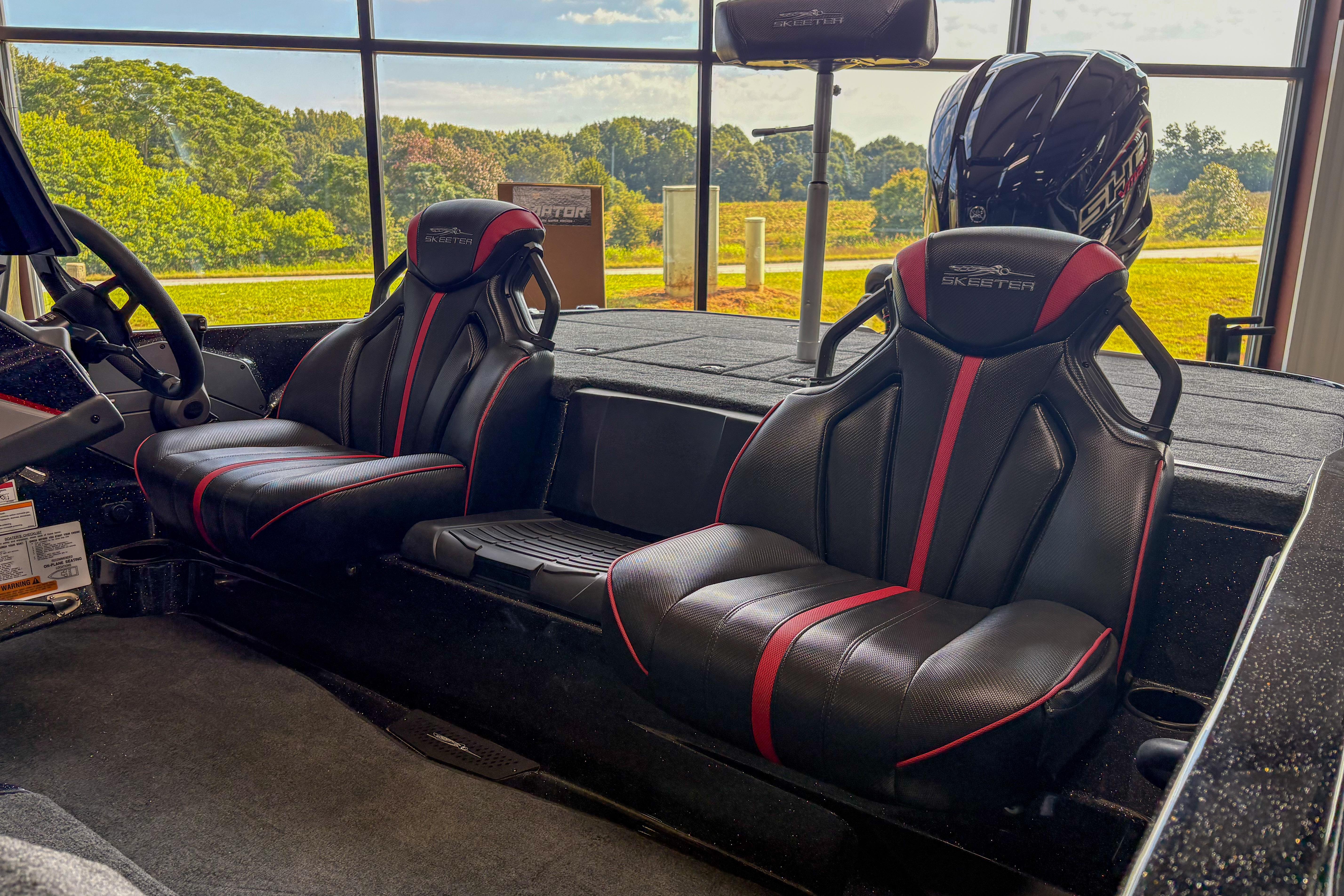 2026 Skeeter ZXE20 boat interior with black and red seats, steering wheel, and outdoor view.