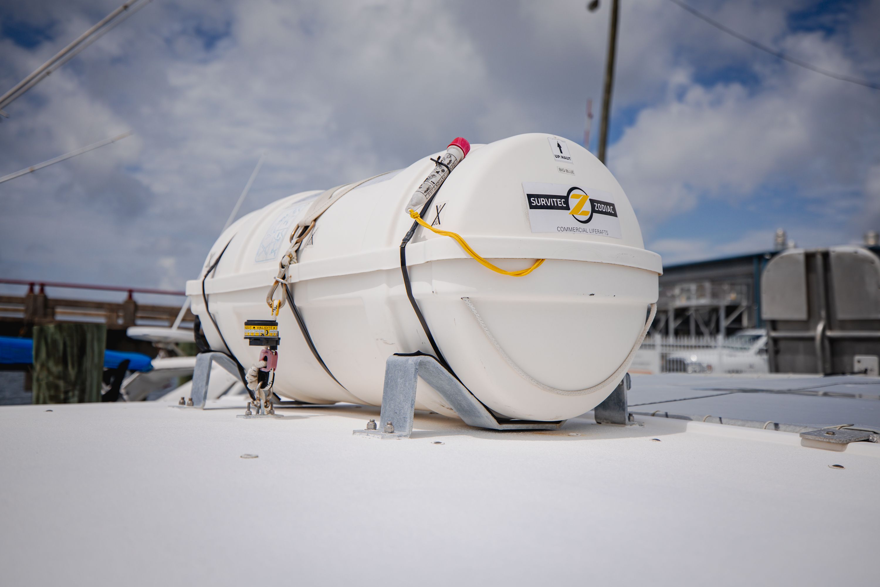 A liferaft is secured on a boat's deck, surrounded by a marina.