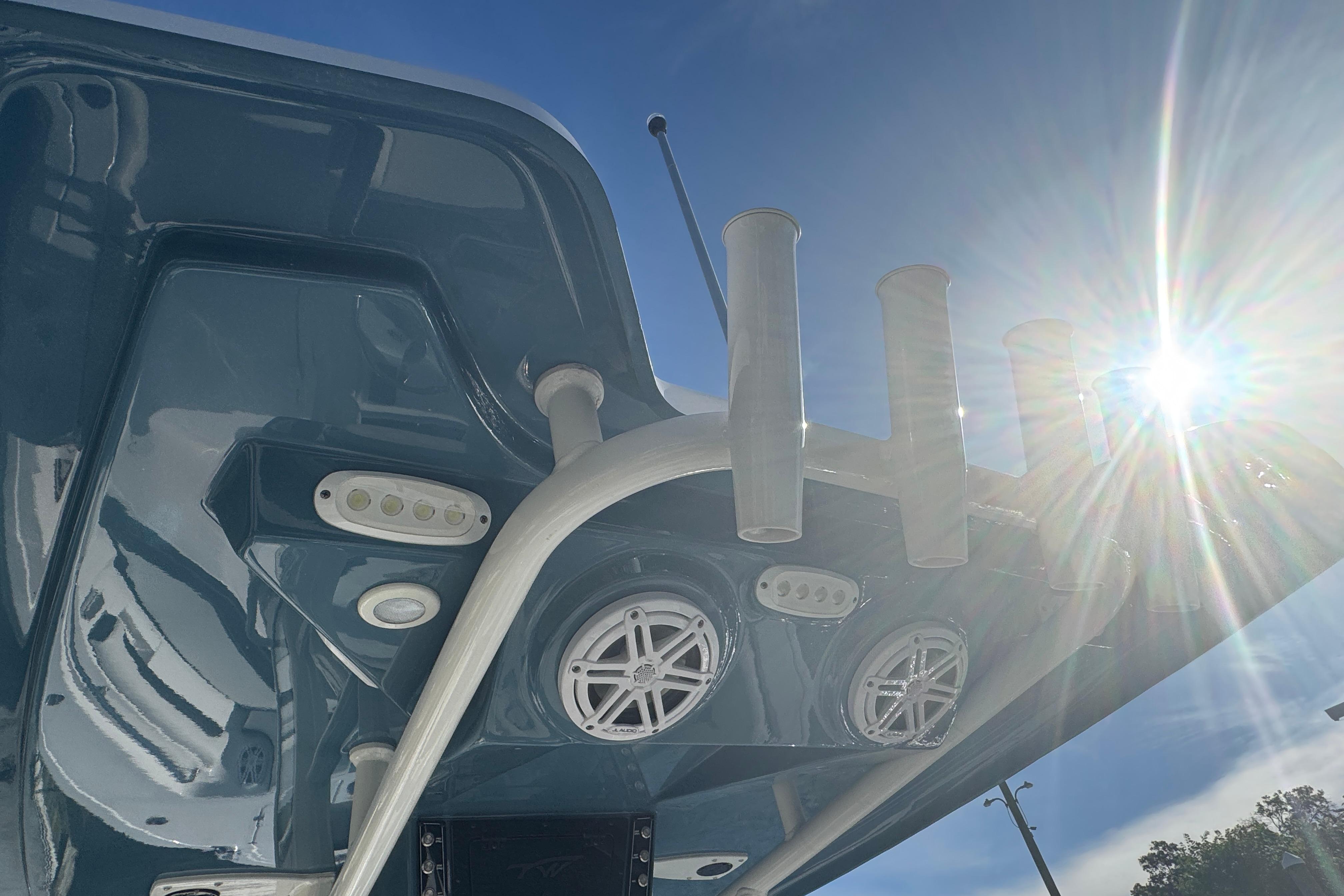 2025 Tidewater 232 LXF boat with rod holders and speakers, sunlit view.