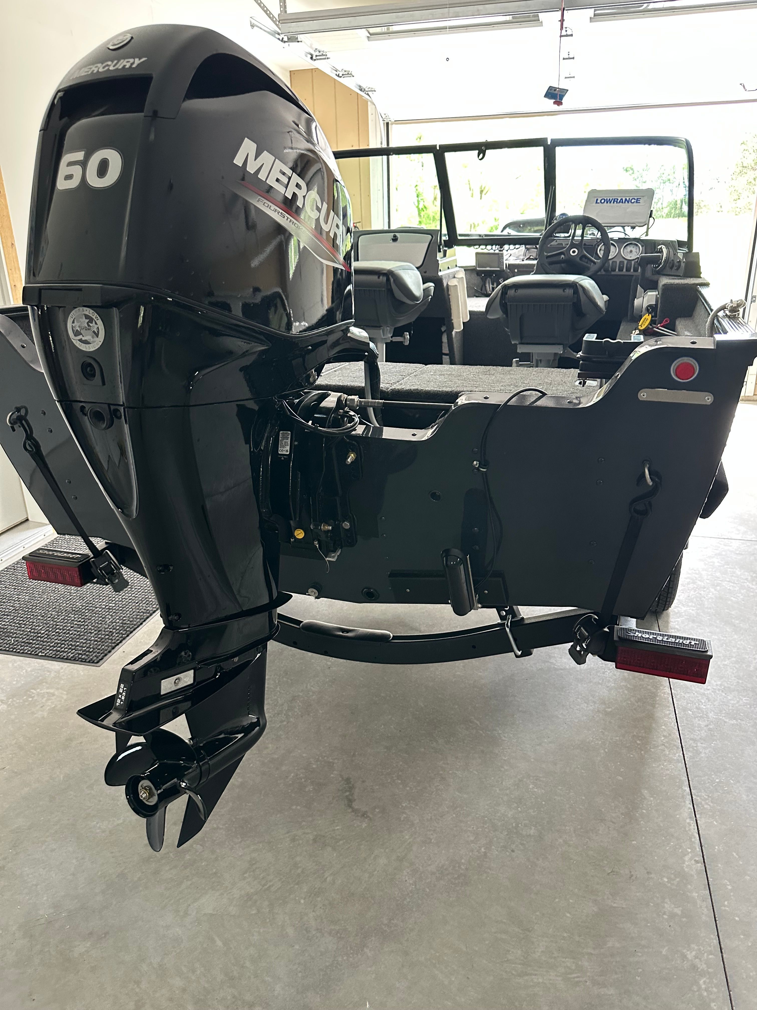 A 2025 Lund Pro Angler 1650 with a Mercury 60 HP outboard motor in a garage.