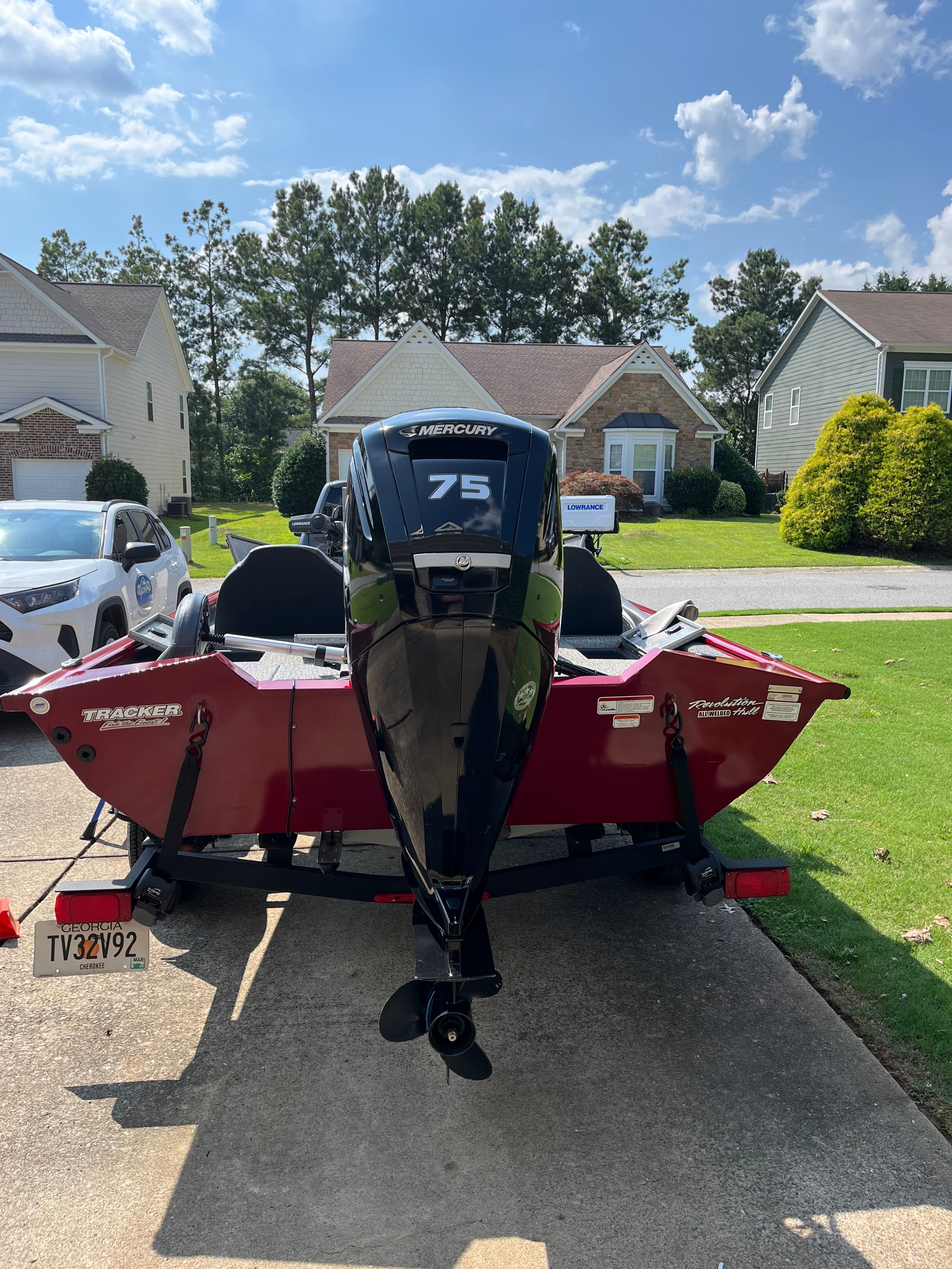 A red 2022 Bass Tracker PRO 175 TEAM TXW Tournament Edition boat on a trailer in a driveway.