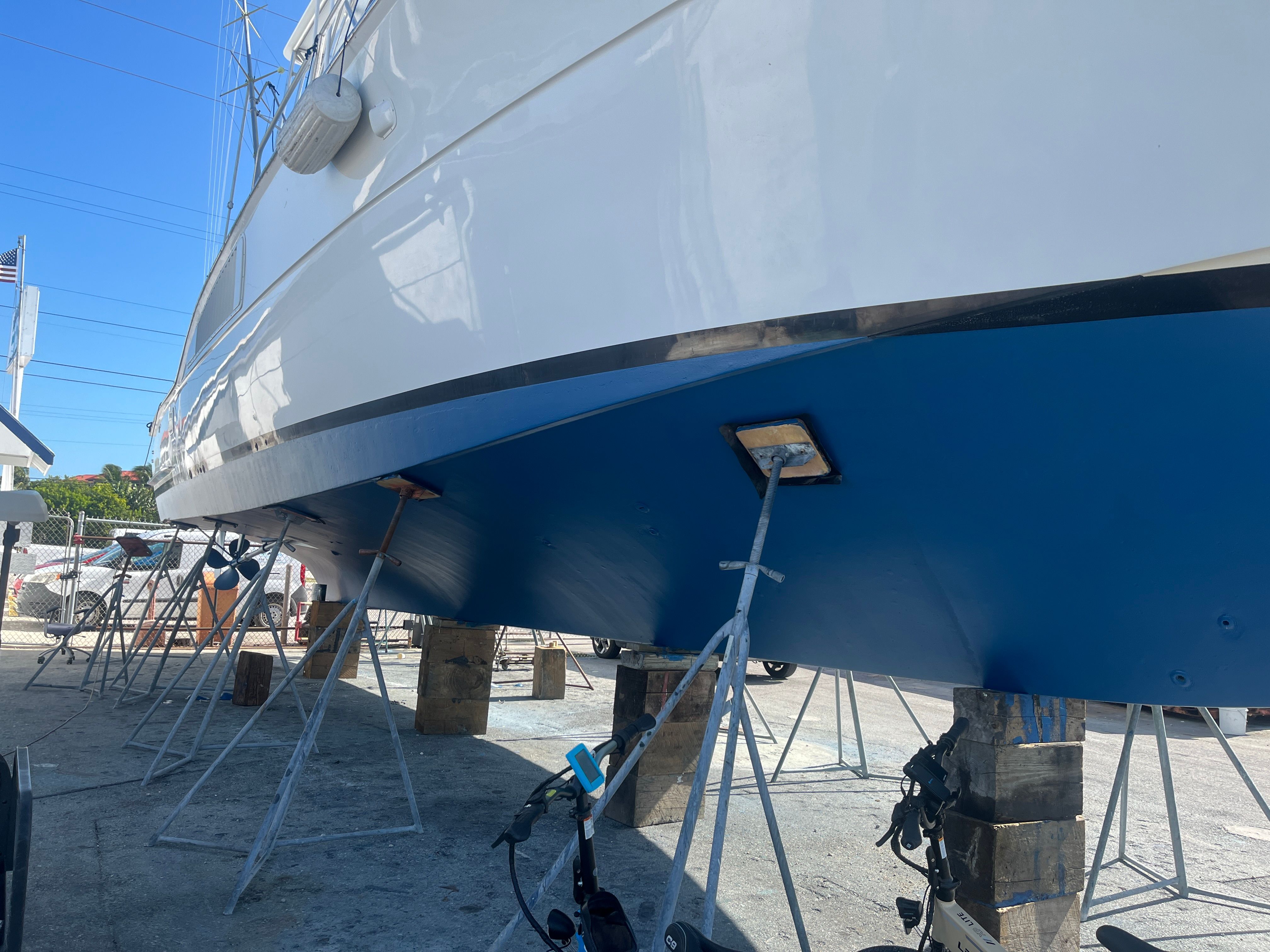 A 1979 Hatteras sport fishing boat is on dry dock, supported by metal stands.
