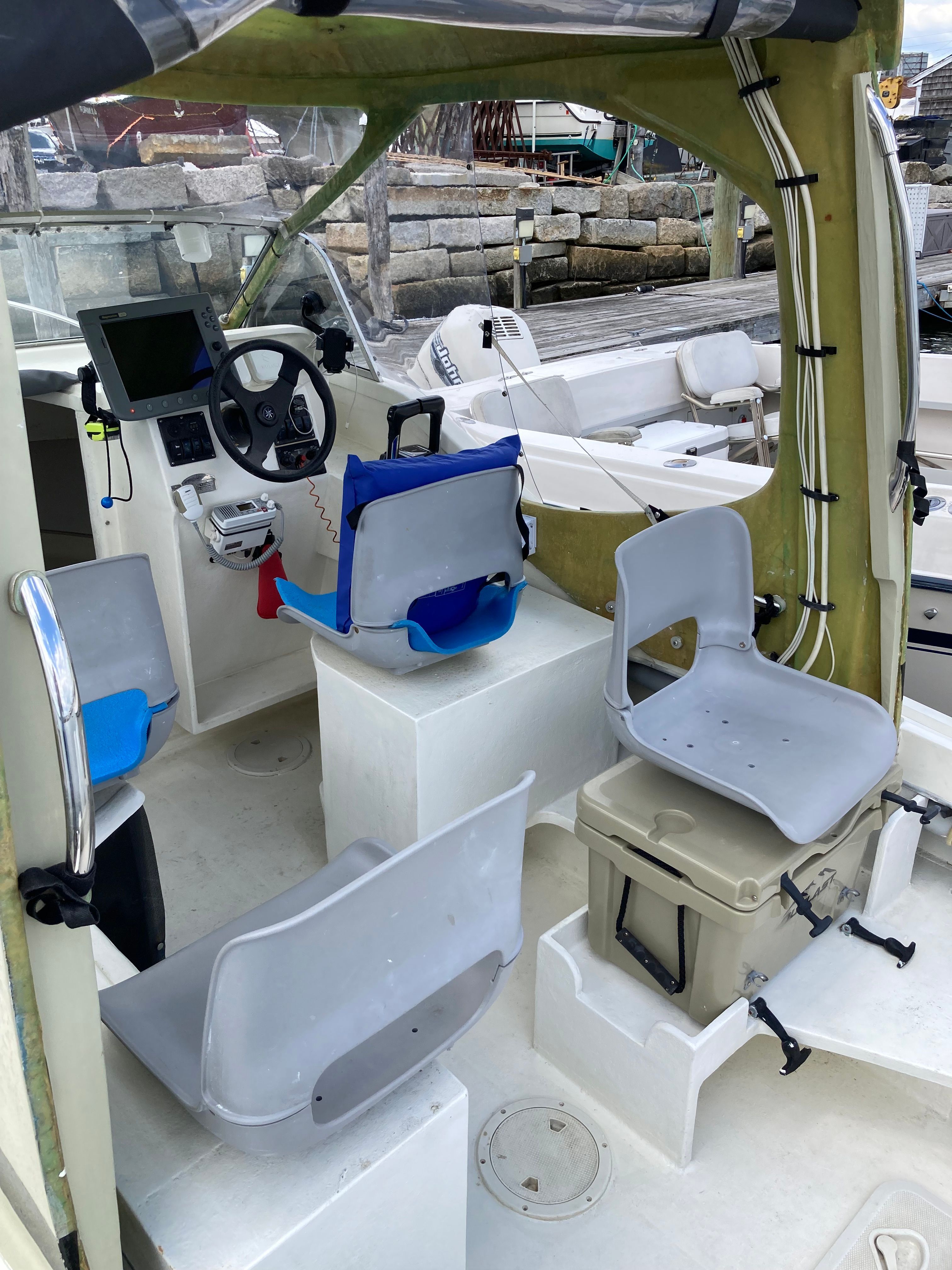 The image shows the cockpit of a 1969 Bertram Bahia Mar with gray seats and a steering wheel.