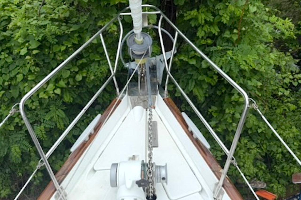 Bow of a 2001 Beneteau 50 sailboat surrounded by lush greenery.