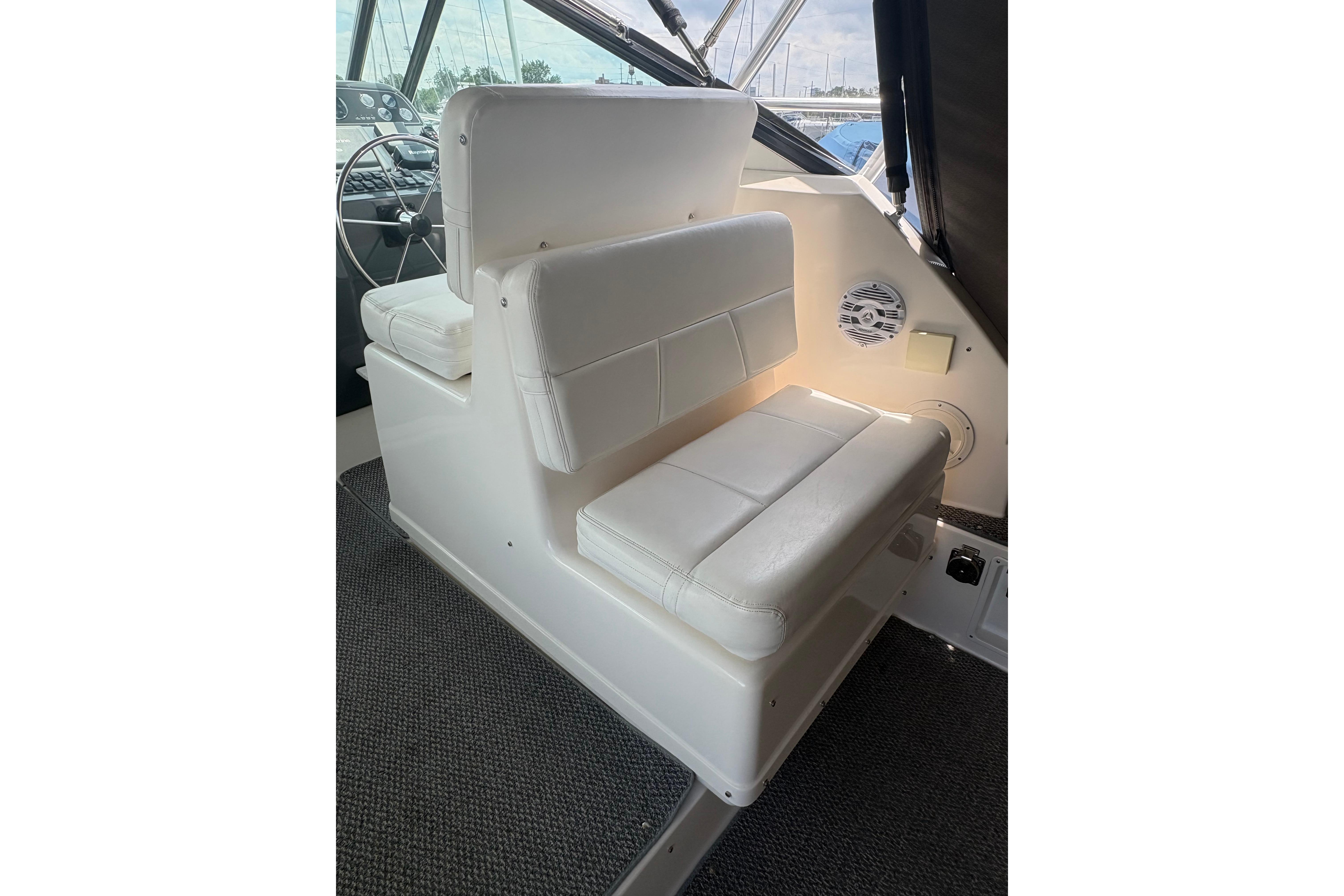 White seating area on a 1999 Tiara Yachts 3100 Open, featuring a steering wheel and speaker.