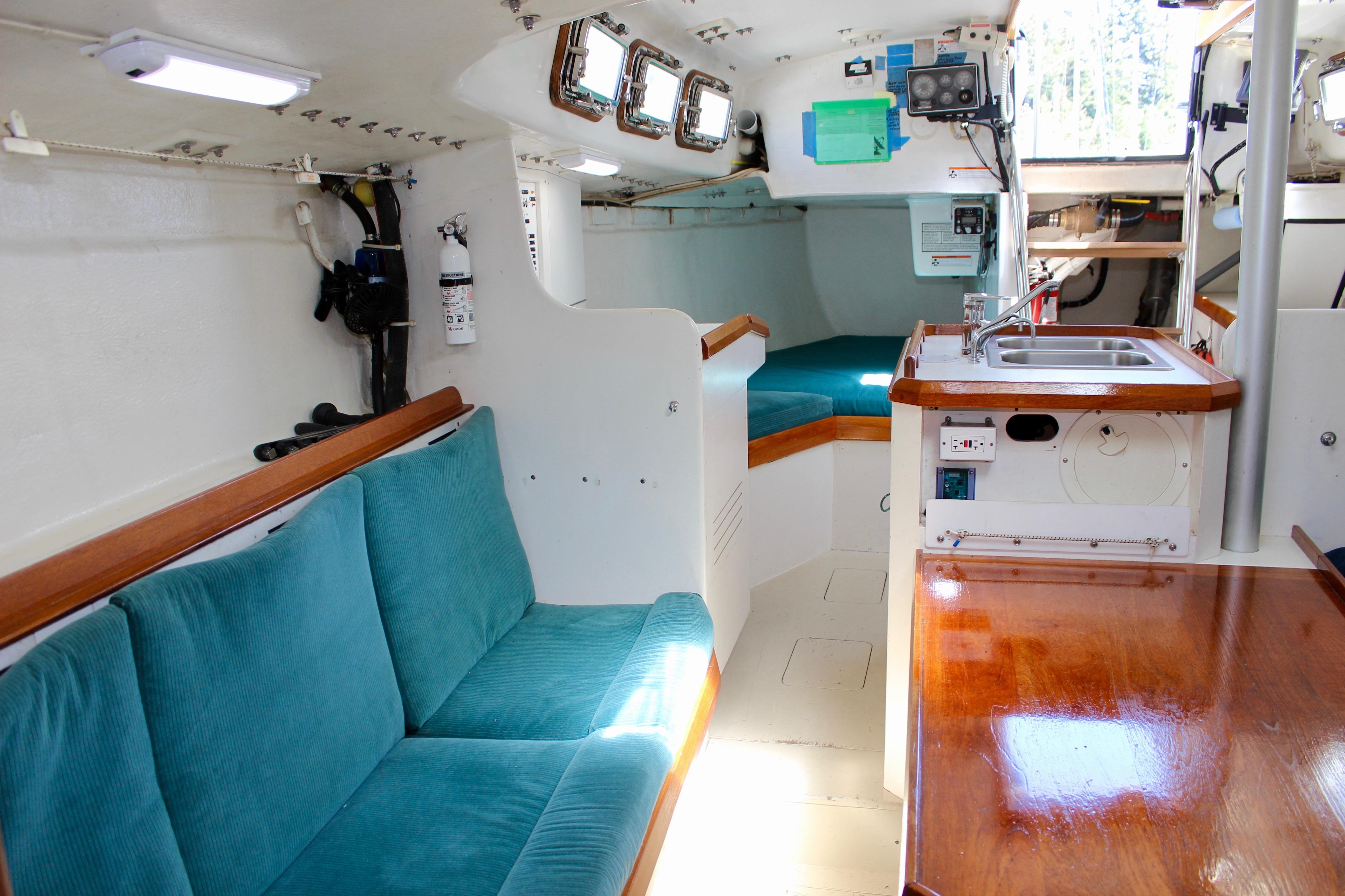 Interior of a 1993 Freya 39 sailboat with teal seating and wooden accents.