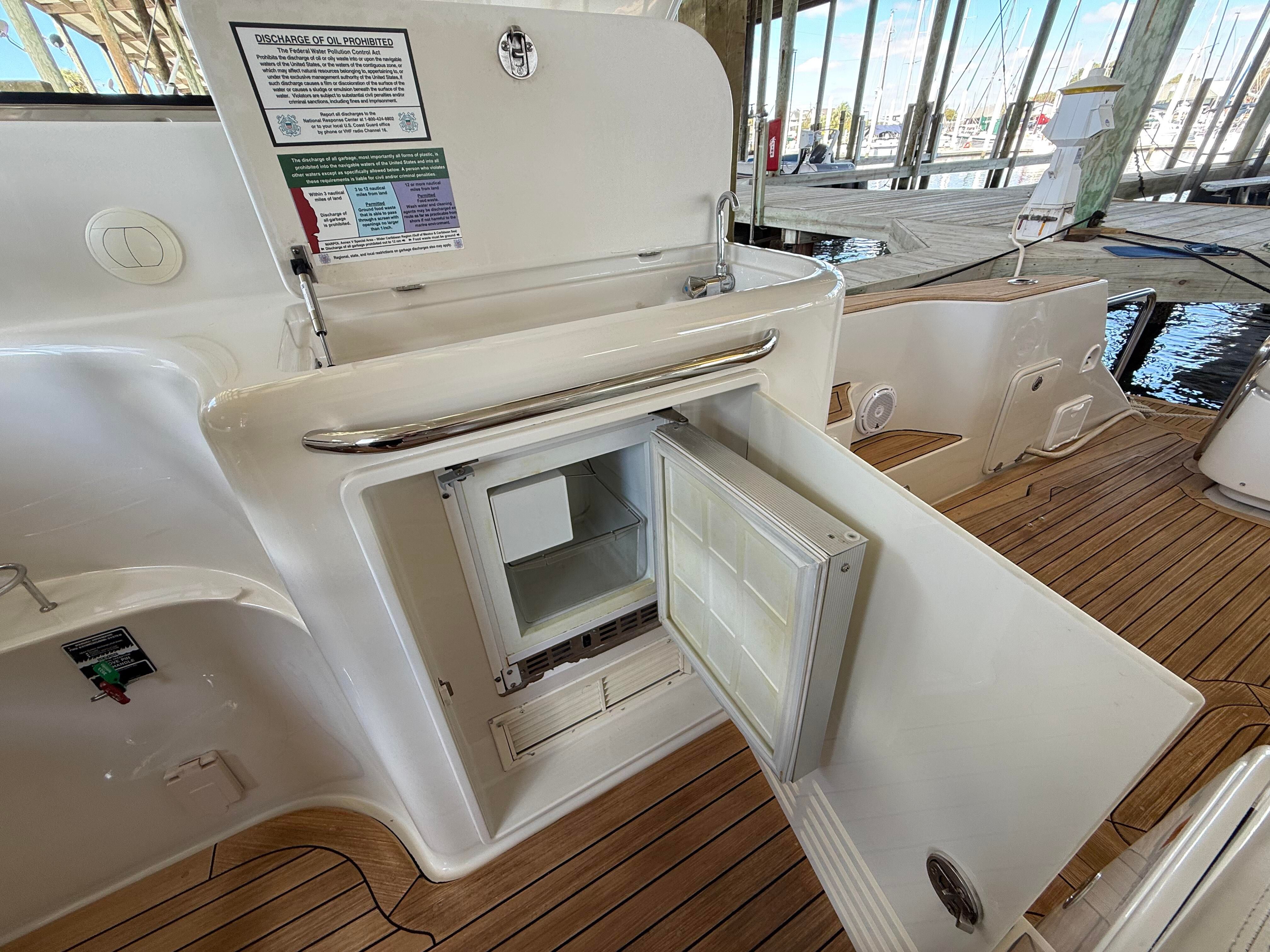 Open refrigerator door on a yacht with a wooden deck.