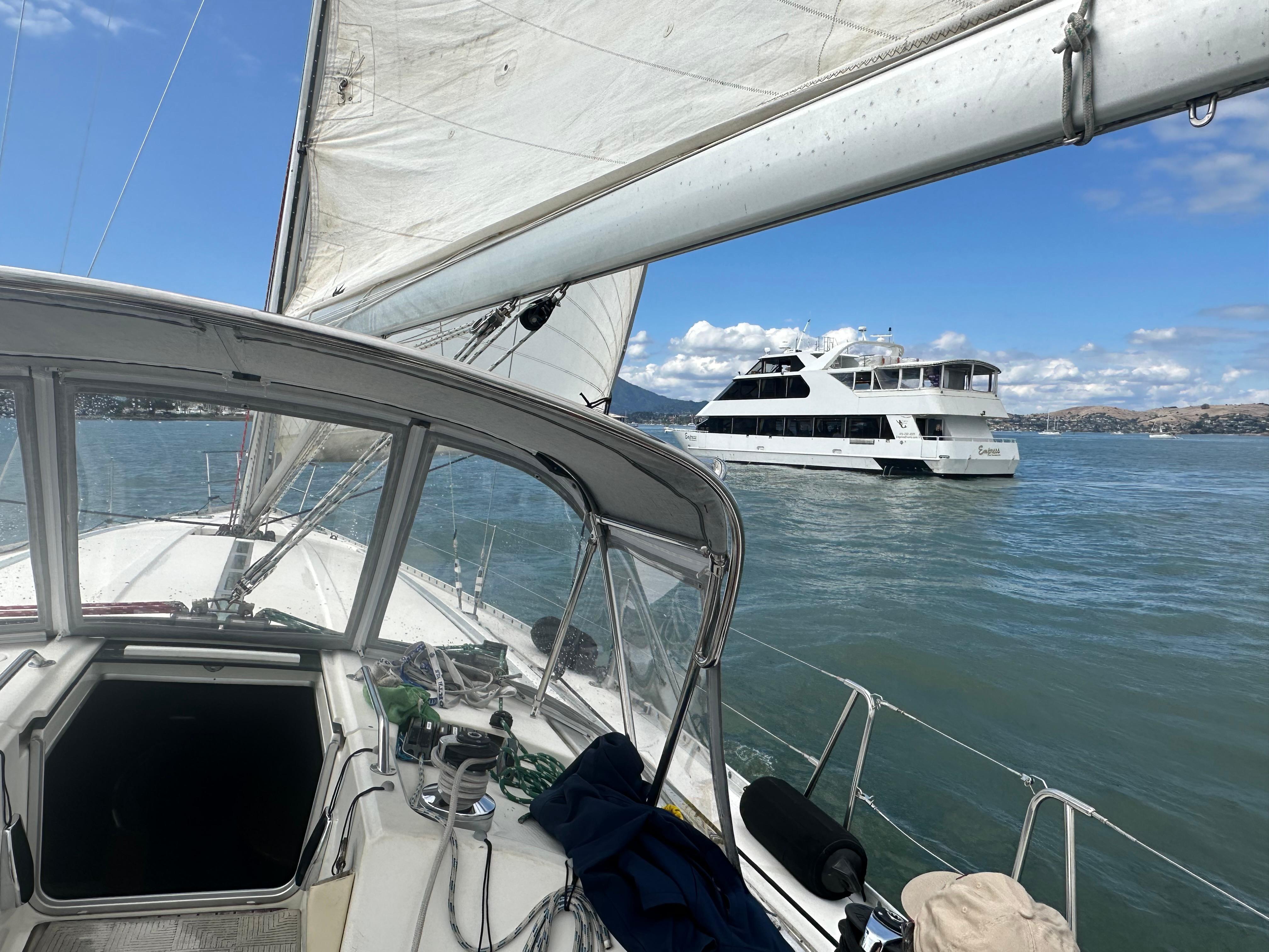 Sailing on a 1991 Beneteau First yacht with a ferry in the background.