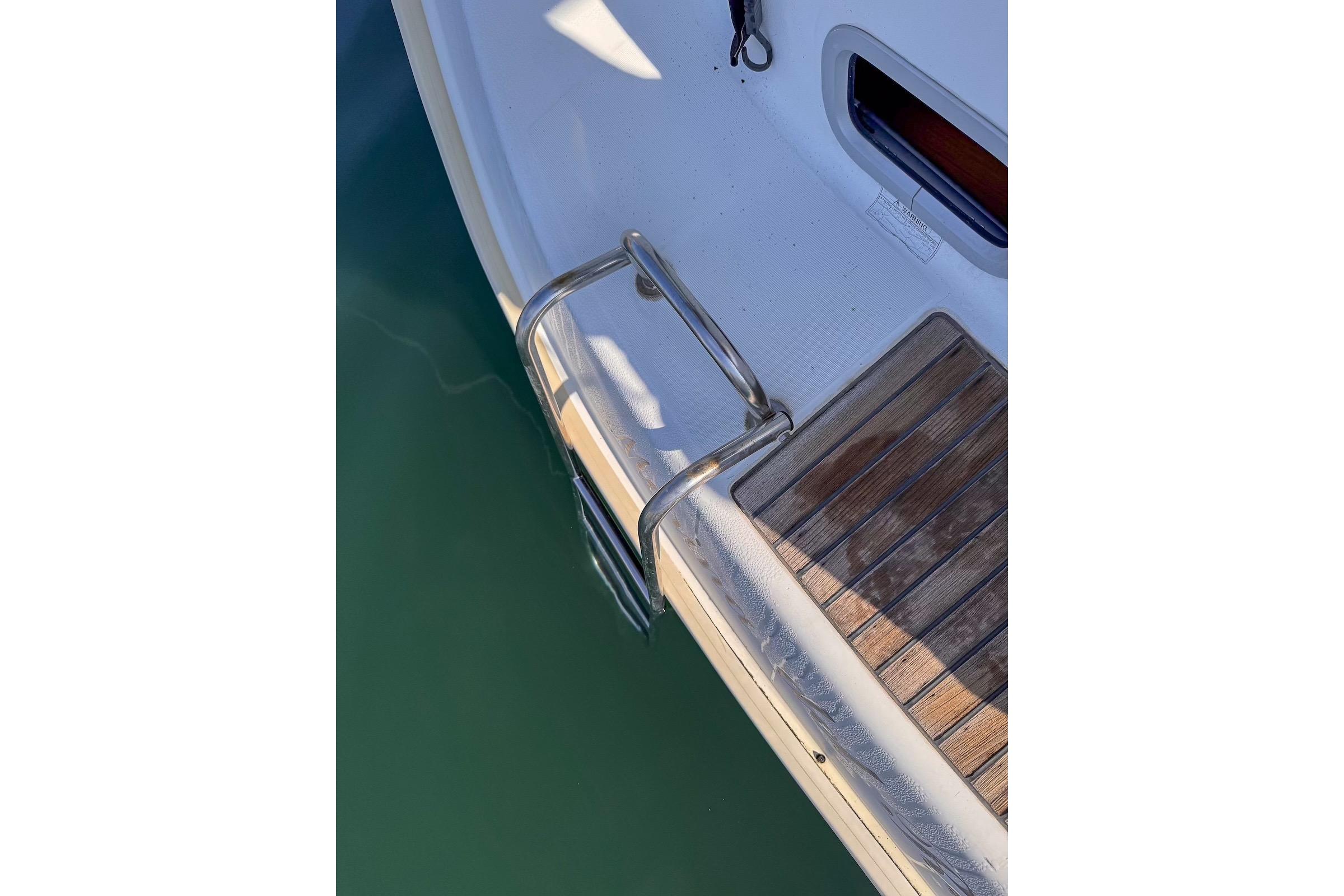 Stern view of 2006 Beneteau 343 sailboat with wooden deck and metal ladder.