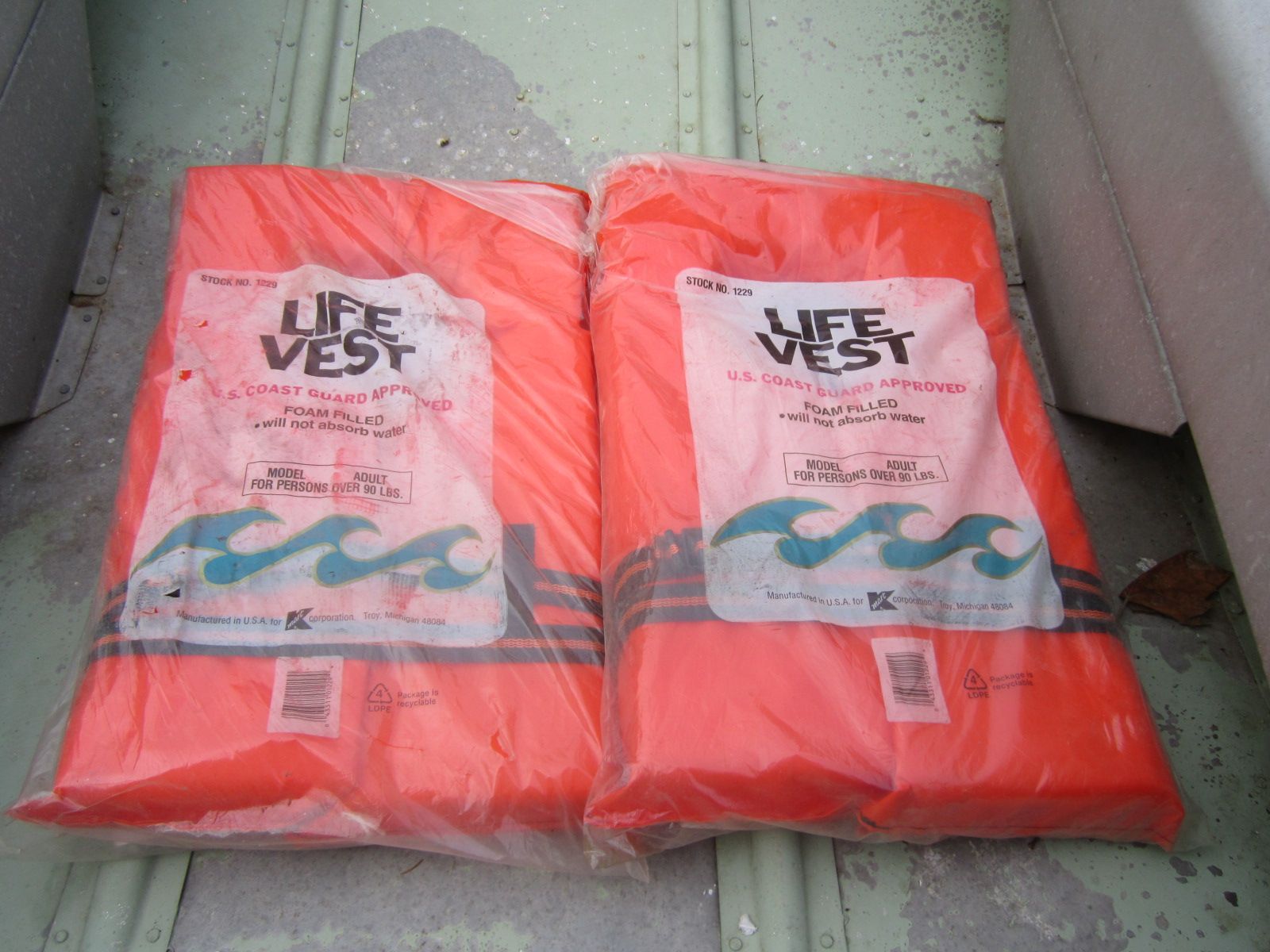 Two orange life vests are lying on a boat floor.